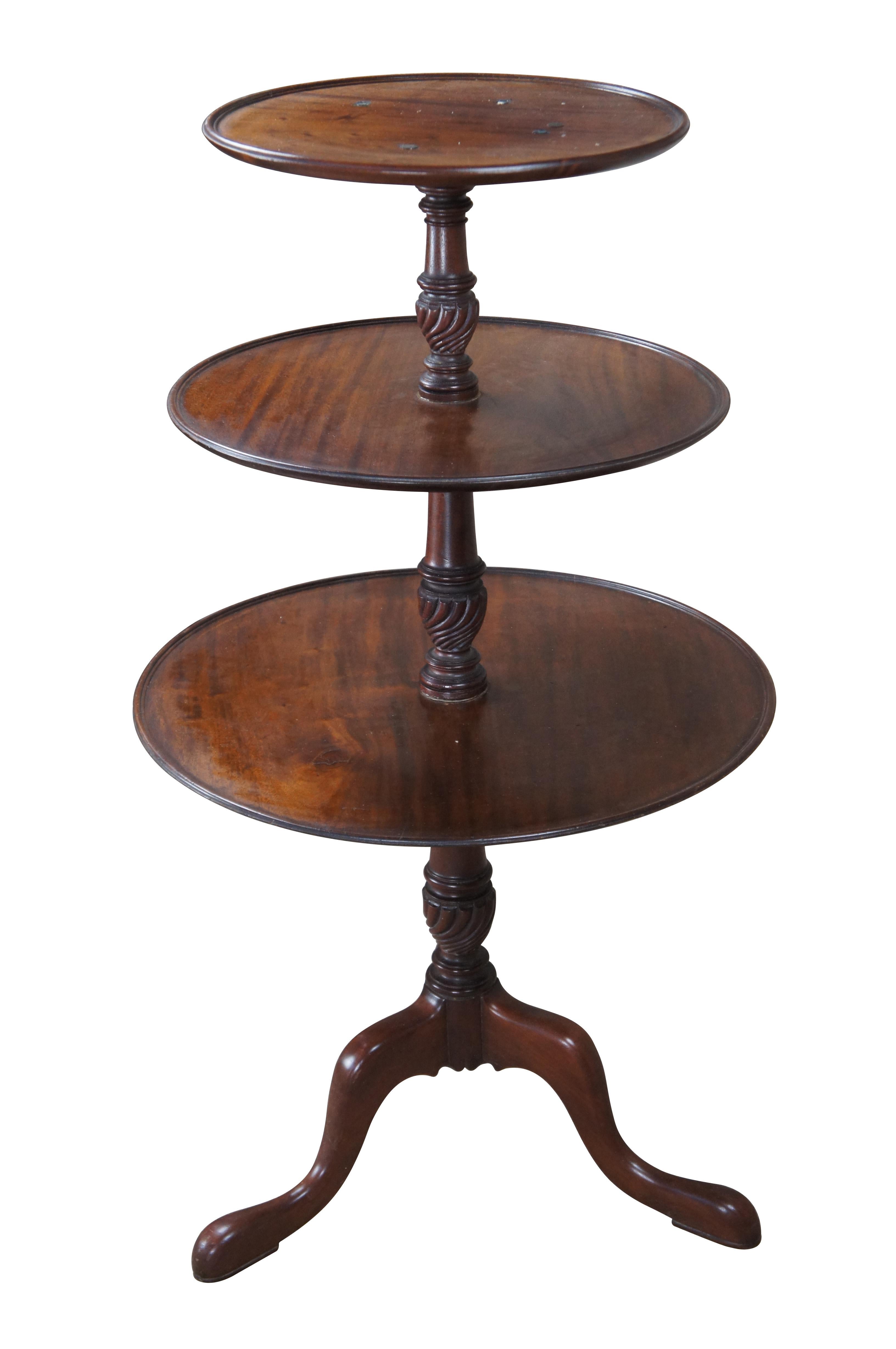 Vintage 20th Century English Georgian butler table. Made from solid mahogany with 3 tiers featuring inset tops connected by turned and carved supports. The table is supported by three downswept legs leading to pad feet.

Dimensions:
41.5