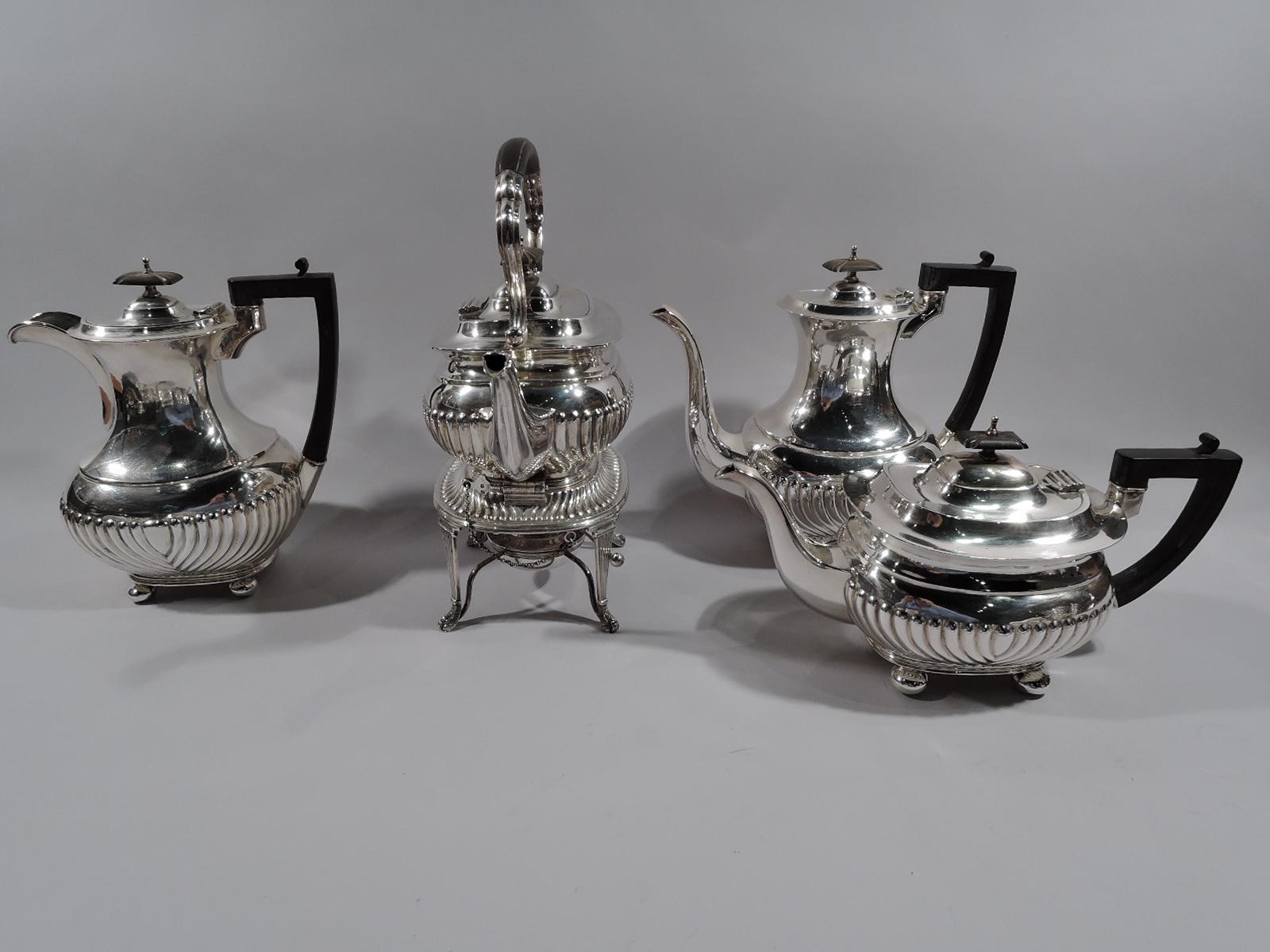 English Georgian sterling silver coffee and tea set, 1918-1919. This set comprises tea kettle on stand, coffeepot, teapot, hot water pot, creamer, sugar, and waste bowl.

Traditional with gadrooned bodies and squashed ball supports. Covers domed
