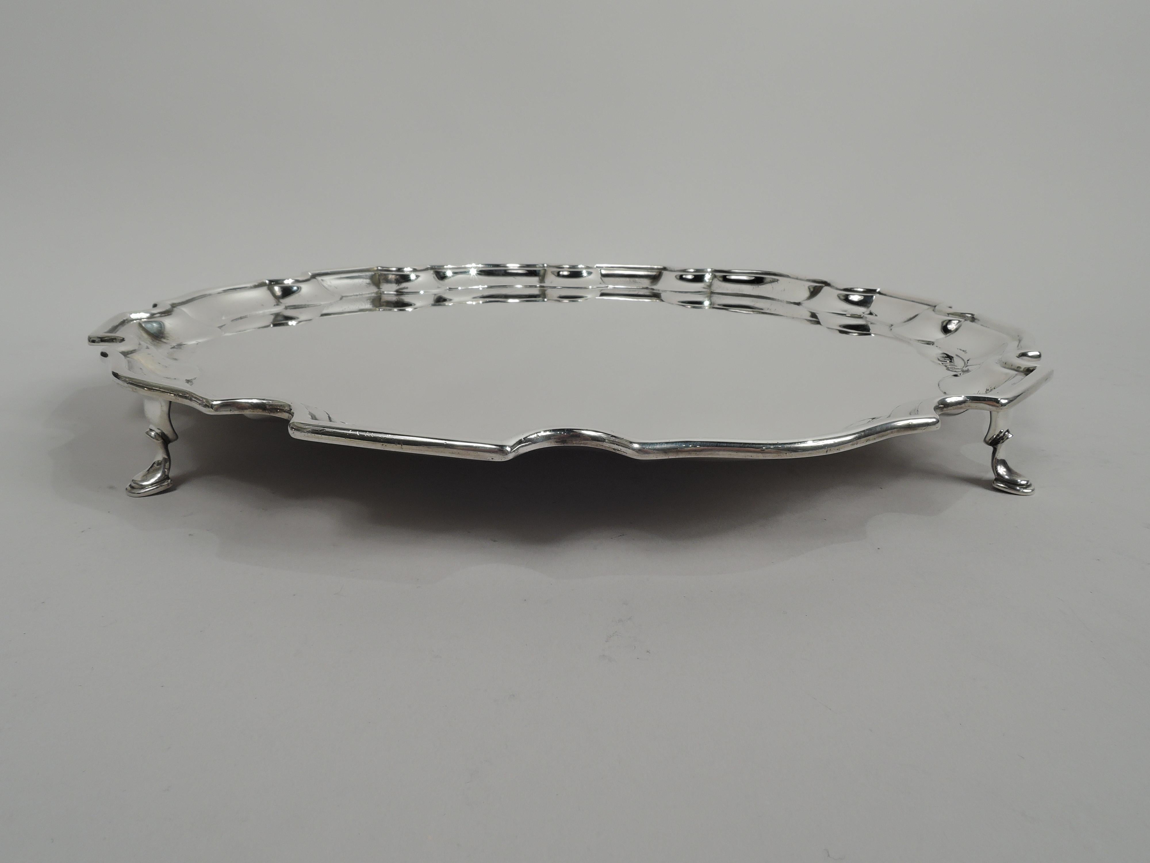 English Georgian sterling silver salver, 1936. Round with molded curvilinear piecrust rim. Rests on four hoof supports. Traditional with nice heft. Fully marked including Selfridge & Co., Ltd retailer’s stamp and Birmingham assay stamp. Weight: 37.5