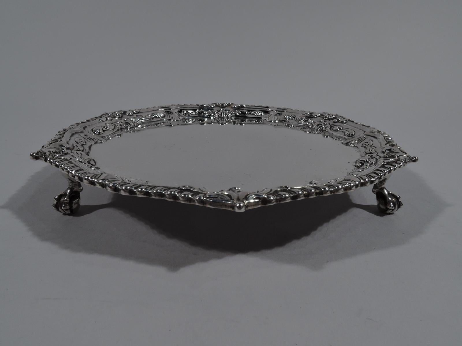 George III sterling silver salver. Made by Ebenezer Coker in London in 1767. Round with leaf and gadroon rim. Three claw-and-ball feet. Four letter monogram engraved on underside. Affordable midcentury Georgian by a noted silversmith. Fully marked.