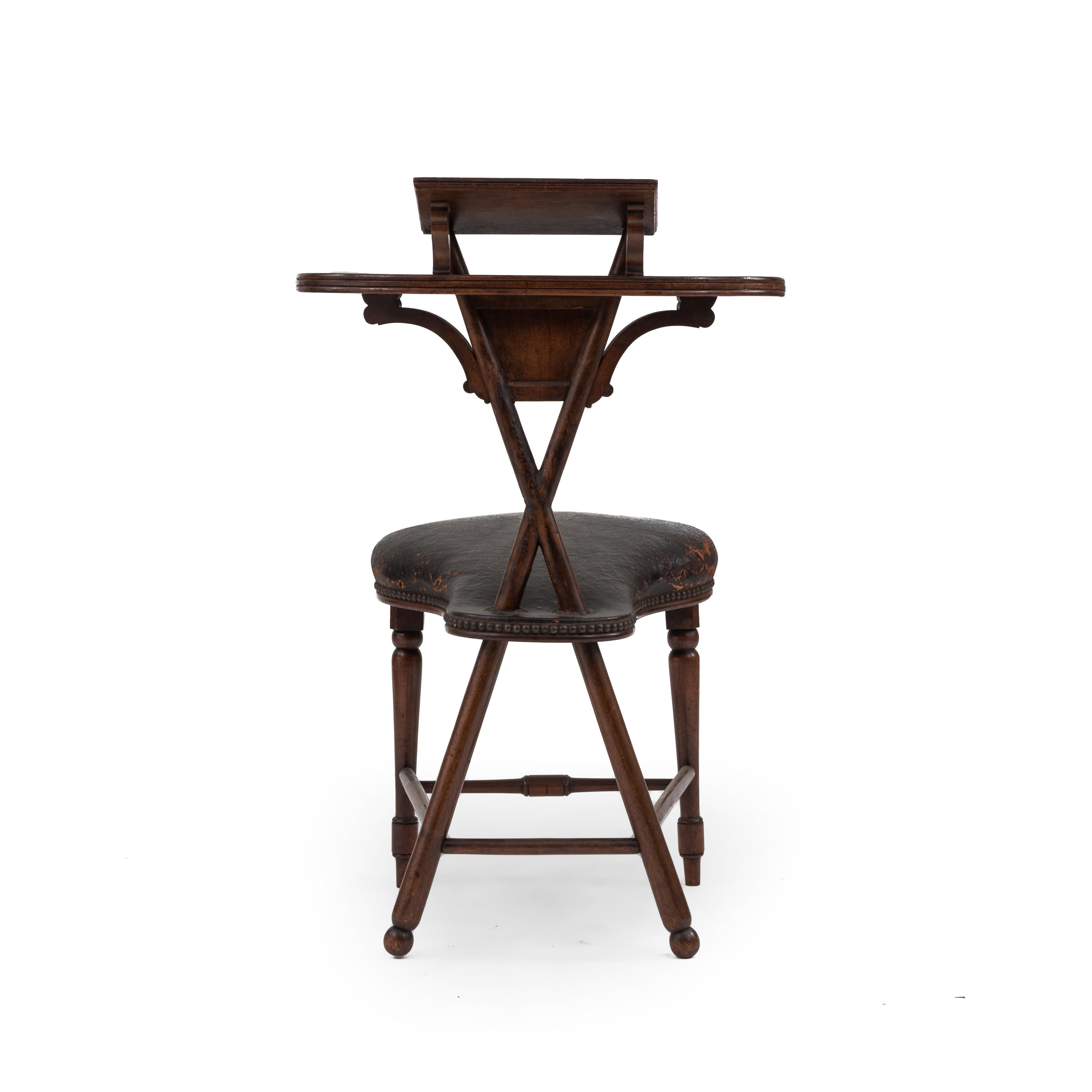 English Georgian style (19th century) Thomas Jefferson walnut reading chair with brown leather seat and open cross design back with book shelf. A rare mid-19th century reading chair. The owner sat astride the saddle seat facing the back of the chair