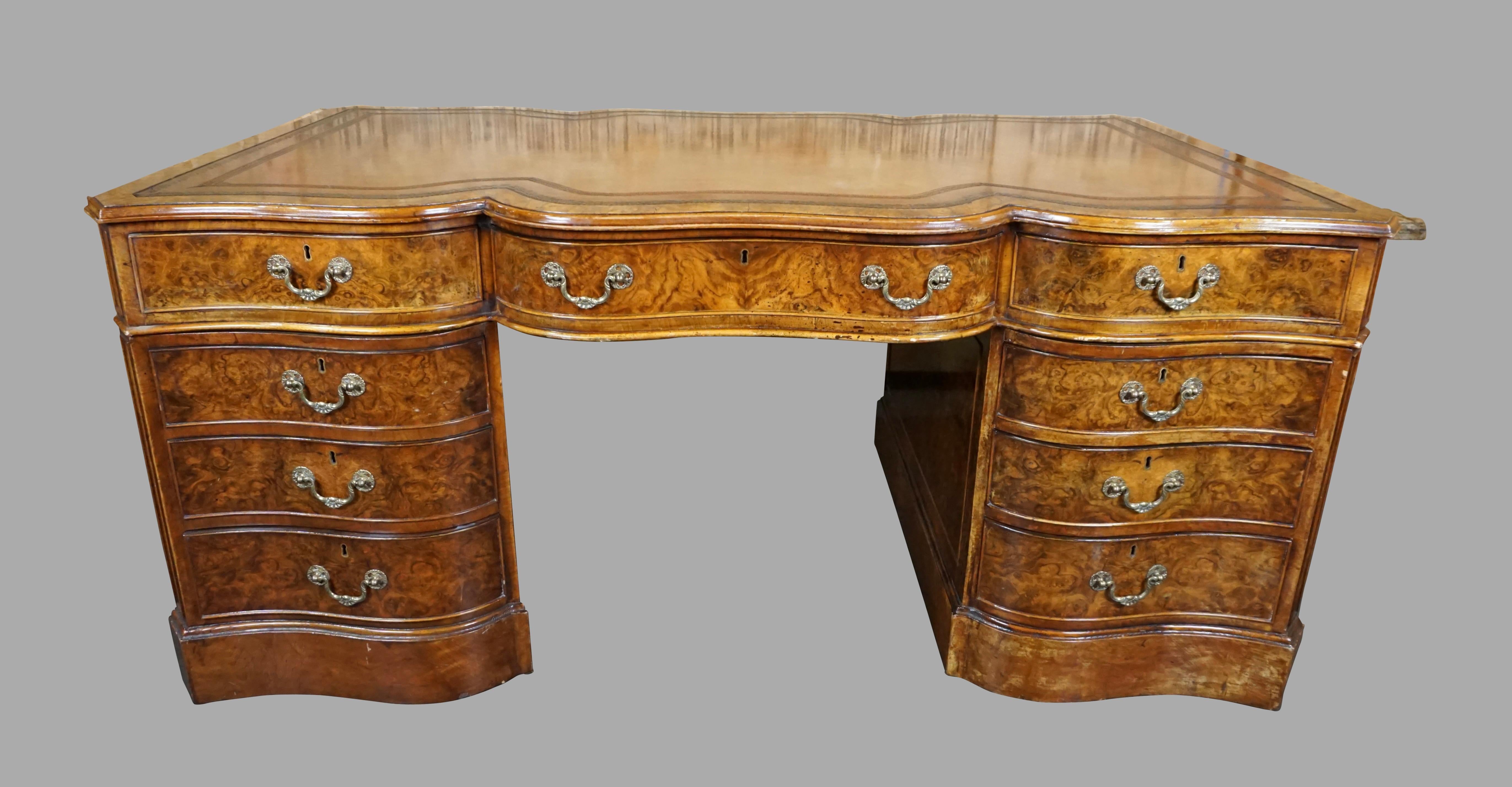 A beautifully crafted English Georgian style burl walnut partners desk of serpentine form, the tooled brown leather top above 3 frieze drawers resting on 6 additional drawers, the reverse fitted with cabinets below the frieze drawers, all on a