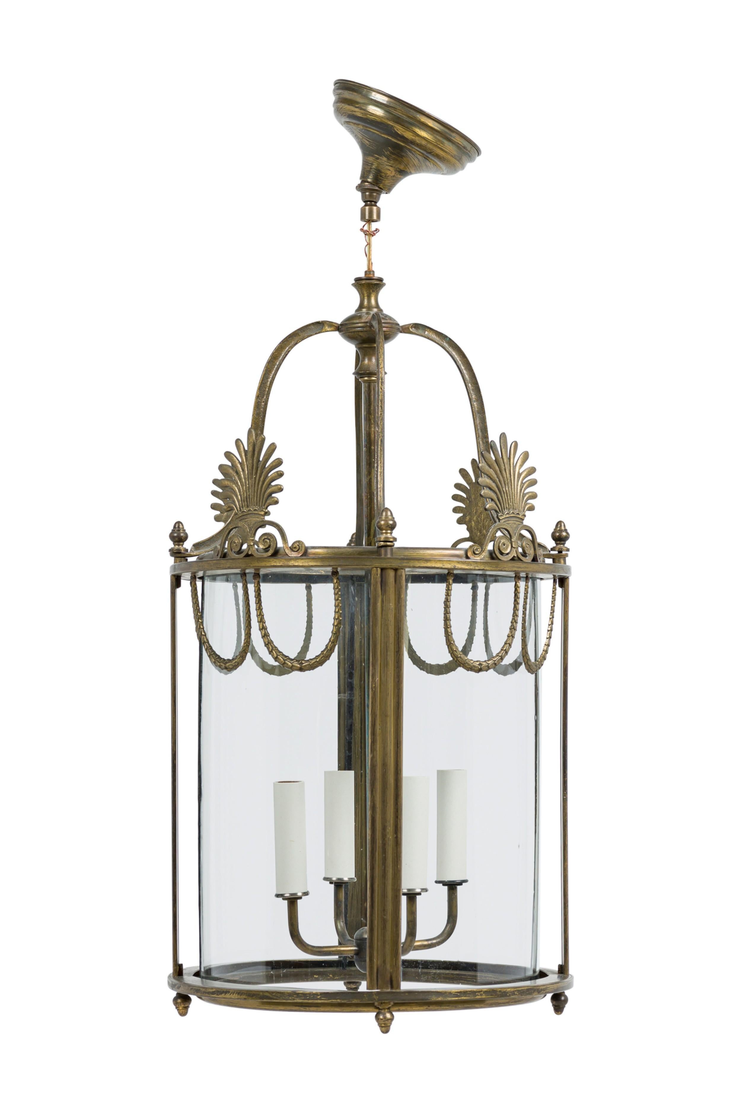 English Georgian style (20th Century)cylindrical brass lantern style with decorative fan shaped finials above 4 curved glass panels, and rope-like swags accents along the top having 4 interior candle lights