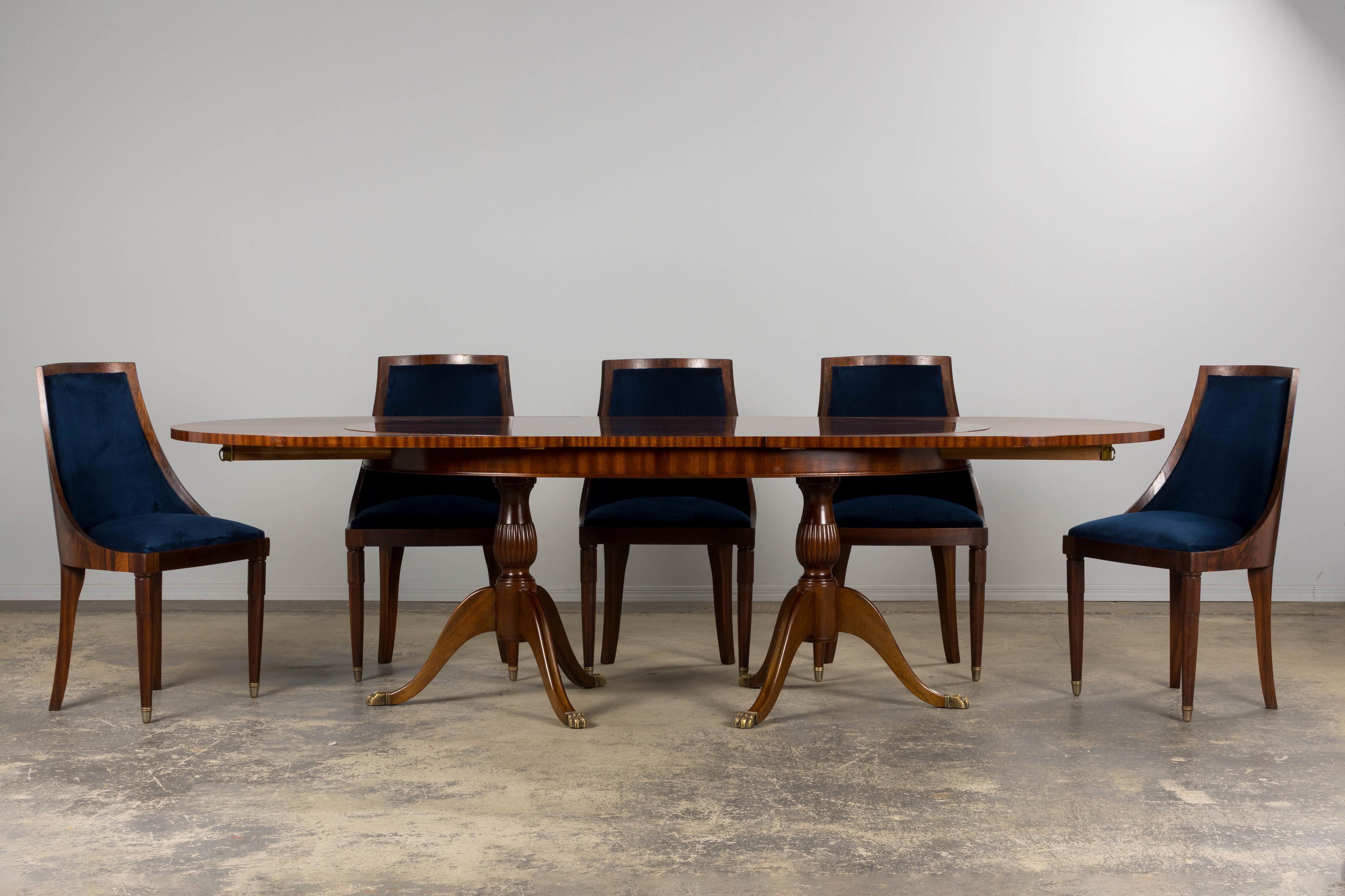 A stately mid-20th-century English Georgian-style extendable double pedestal dining table, made in France and sourced from Provence. Expertly handcrafted from solid flame mahogany, the table features a richly figured oval top that extends from