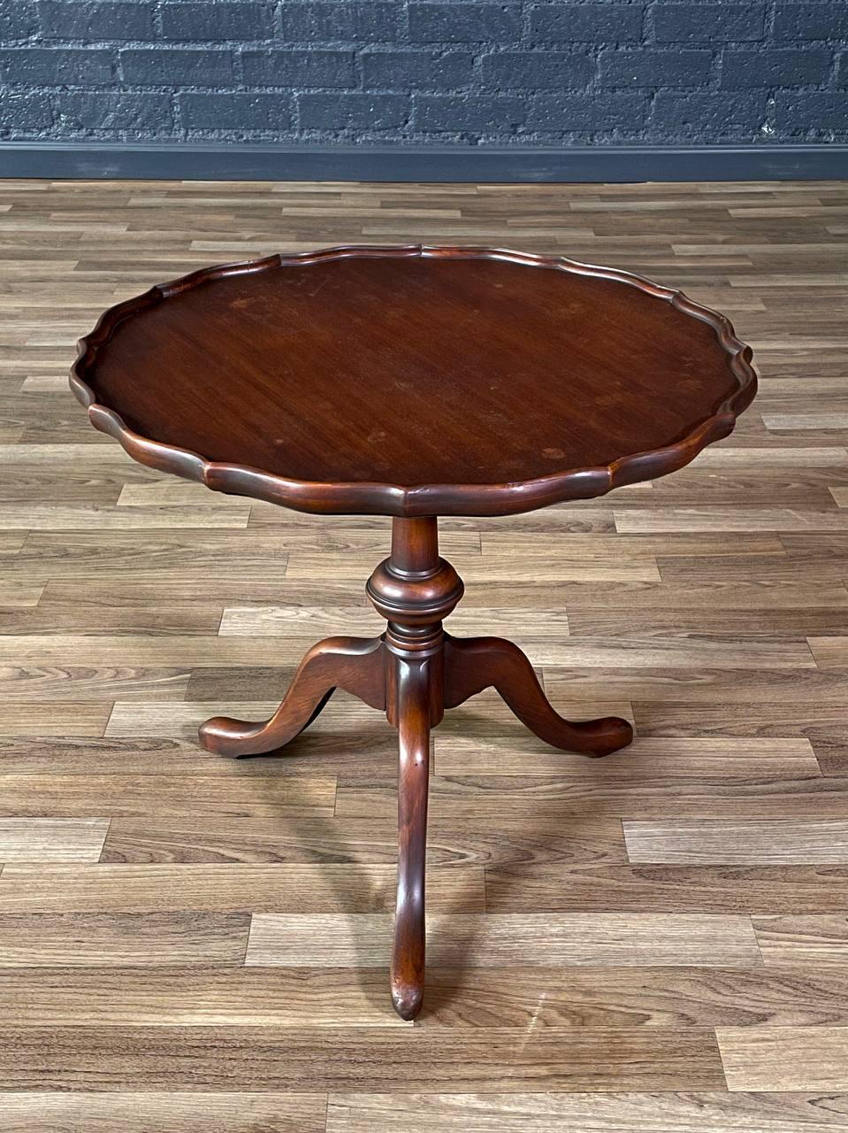 Condition: Original Vintage Condition
Style: English Georgian

This vintage mahogany pie-crust side table, crafted in the 1940s, draws inspiration from the elegance of English Georgian design. Its scalloped edge, turned pedestal, and graceful tripod