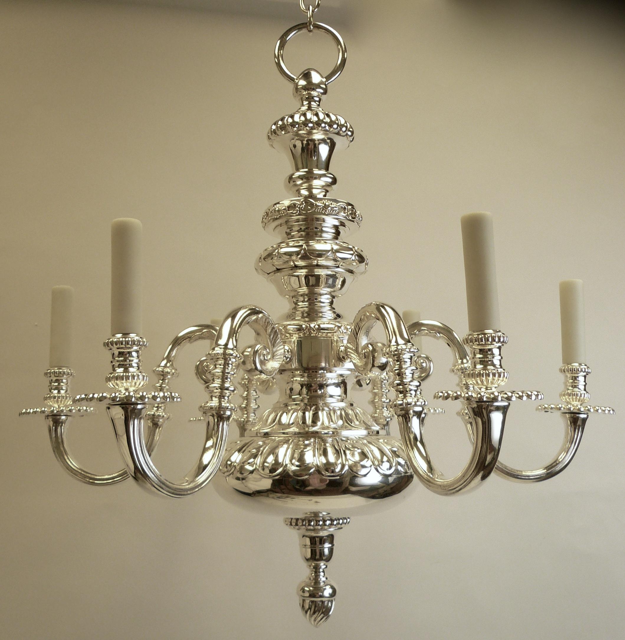 This handsome, heavily cast bronze 'Old English' style six-arm chandelier is finely detailed and plated in silver. This fixture retains it's original signed canopy and chain. It has been polished, lacquered, and re-wired, and is ready for use.