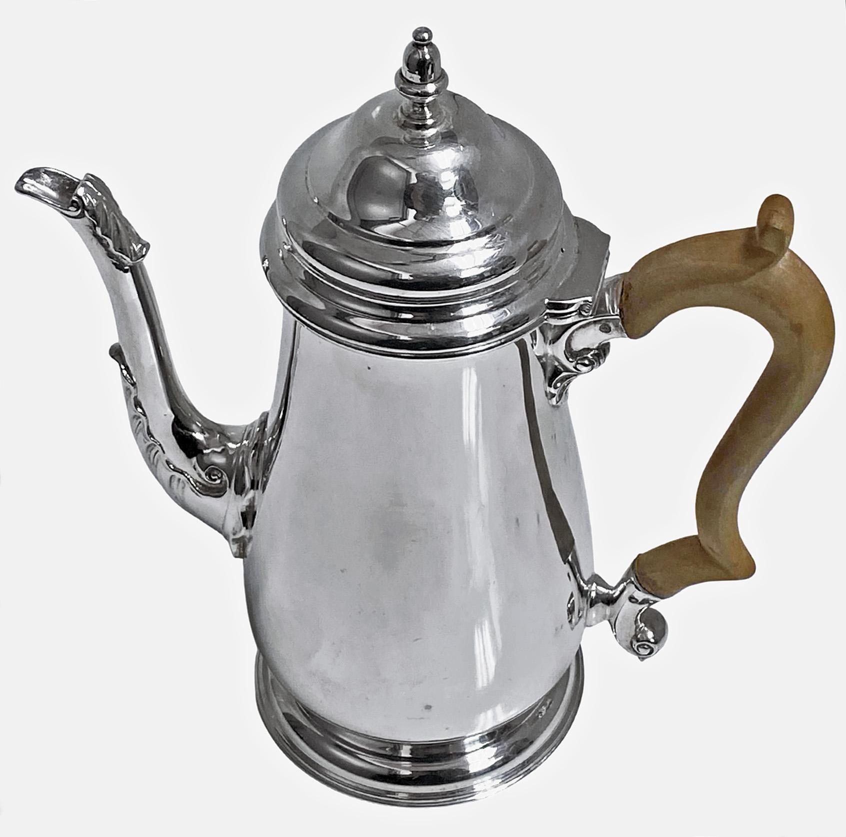 English Georgian style sterling silver coffee pot, London 1965 Wakely and Wheeler. Plain tapered body on pedestal circular foot. The domed, hinged cover lid with silver campana finial, the spout accented with acanthus foliage, fruitwood handle. Full