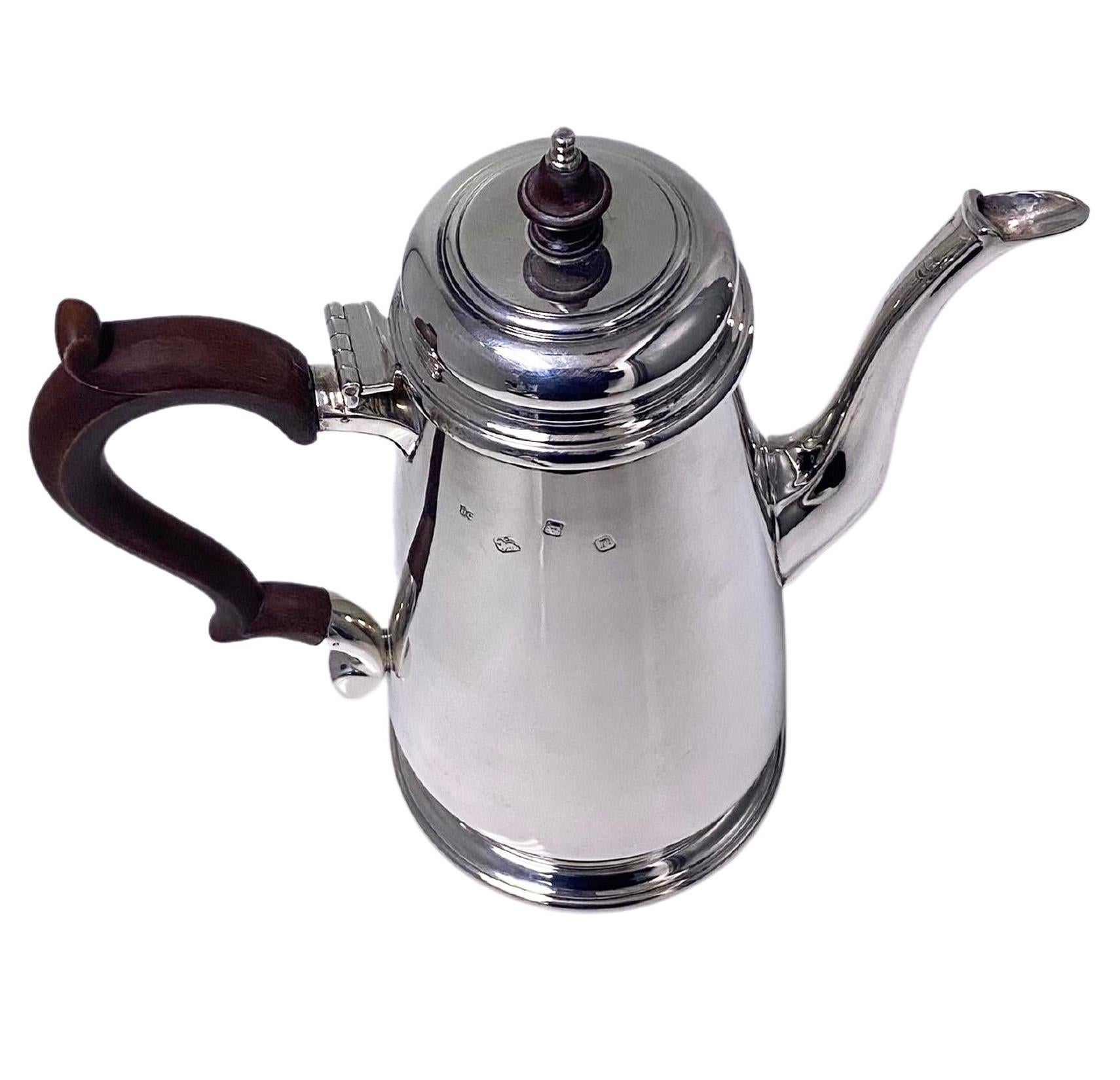 English Georgian style sterling silver coffee pot, London 1968 William Comyns. Plain tapered body on pedestal circular foot. The domed, hinged cover lid with mushroom ebony and silver finial, the plain spout with plain fluting accent, fruitwood