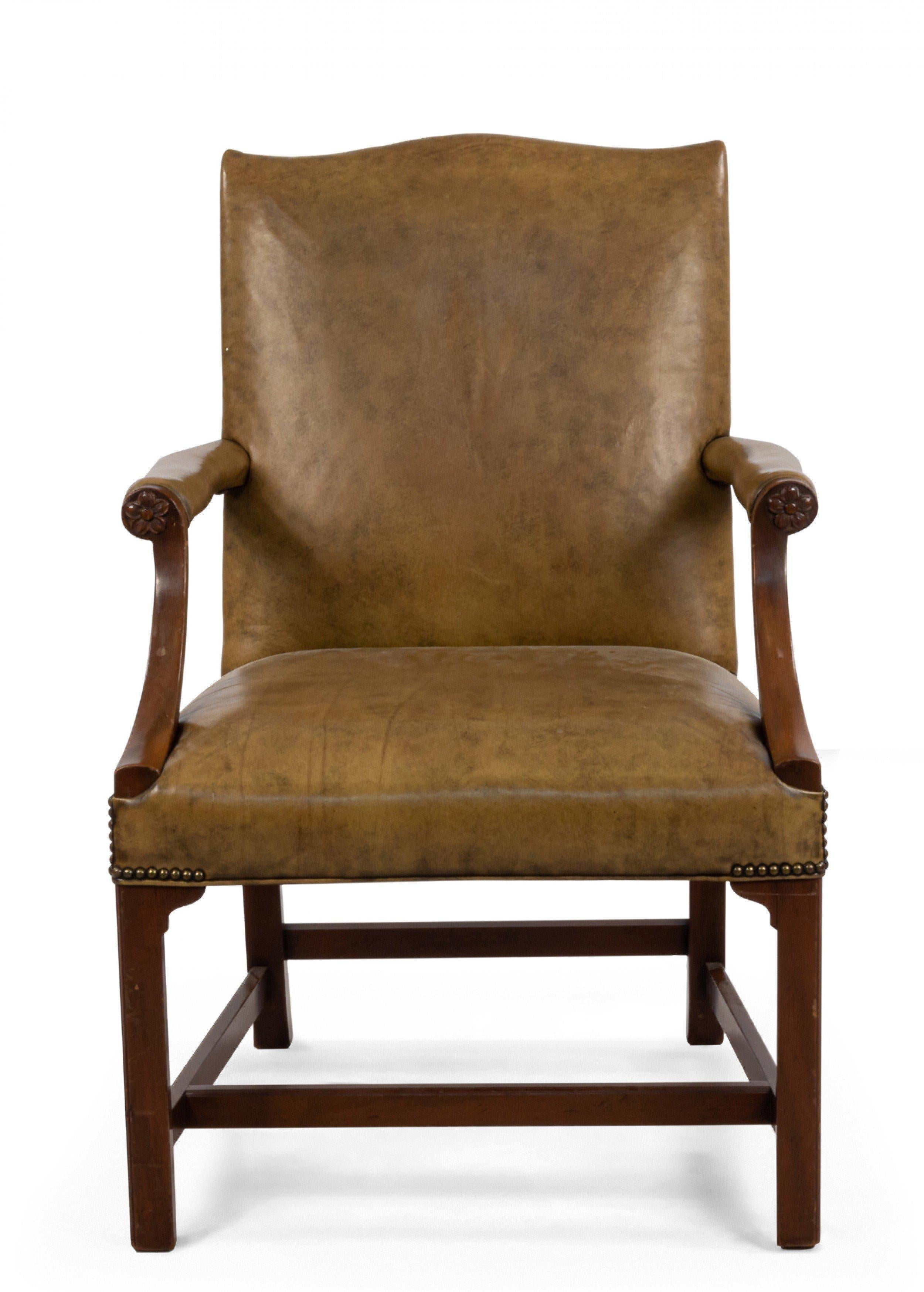 English Georgian style (20th century) armchair with tan leather seat, shaped back and arm rests with brass nail head trim and carved floral detail at arm.