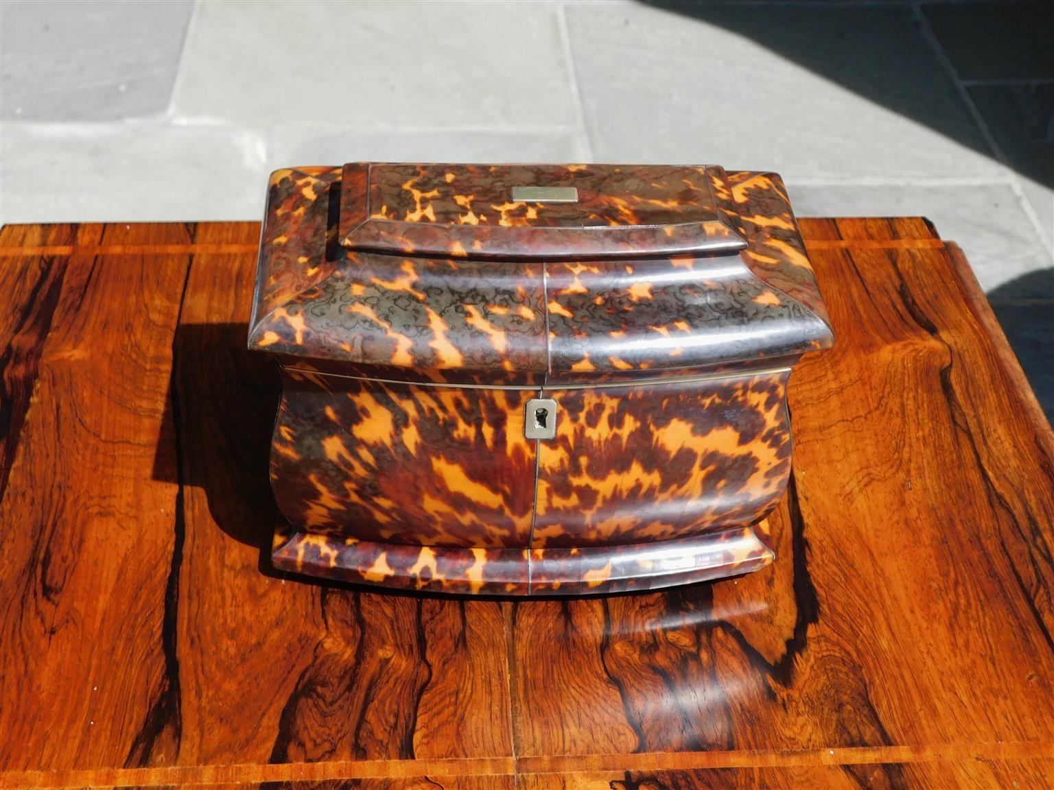 English Georgian tortoise shell hinged tea caddy with a domed tiered lid, squared escutcheon, fitted interior with two lidded tortoiseshell foil lined compartments, and resting on the original four bone feet. Early 19th century.