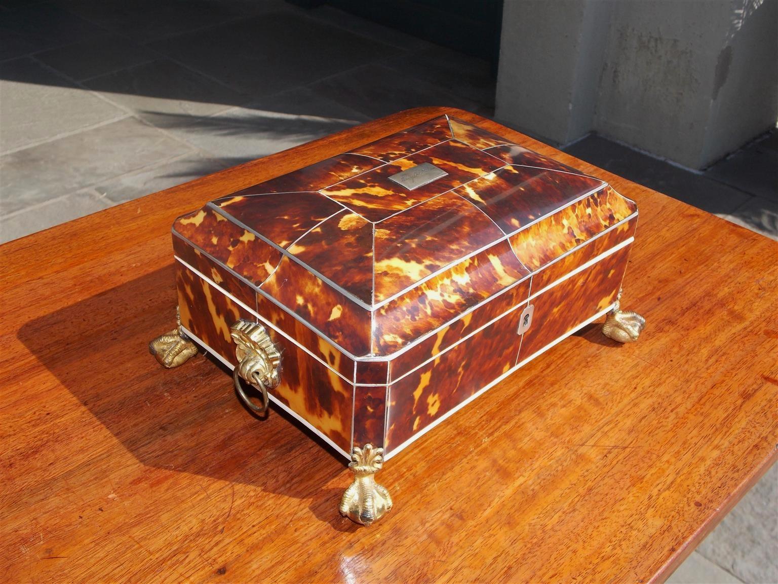 English Georgian tortoise shell hinged sewing box with gilt floral ringed side handles, compartmentalized tufted fitted interior with lid, and resting on the original gilt claw and ball feet. Early 19th century.