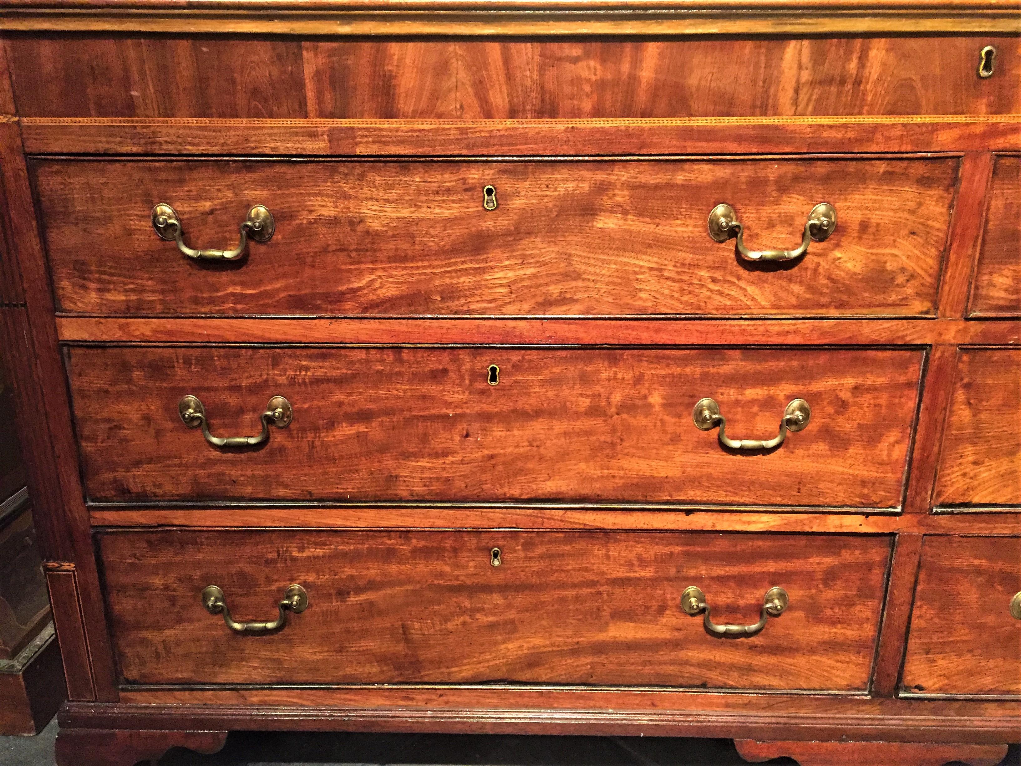 George III, Very nicely grained with a satin like wave throughout. Four (4) working drawers, the top level with faux drawers fronts concealing a storage well reached by the lift top. The bank of drawers are flanked with reeded and inlaid pilasters,