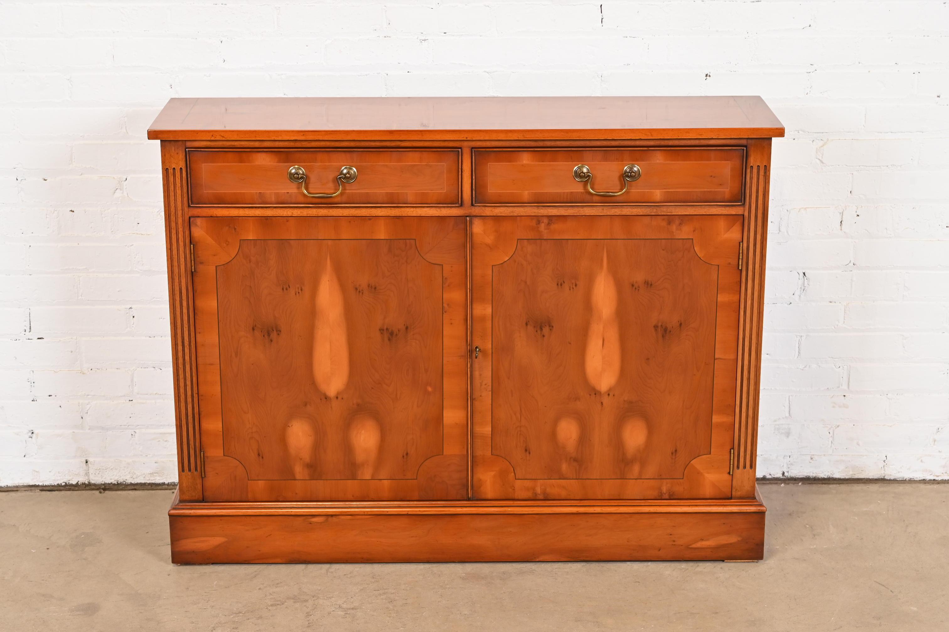 A gorgeous English Georgian style console, buffet server, or bar cabinet

In the manner of Baker Furniture

USA, Circa 1980s

Banded book-matched yew wood, with original brass hardware. Cabinet locks, and key is included.

Measures: 45
