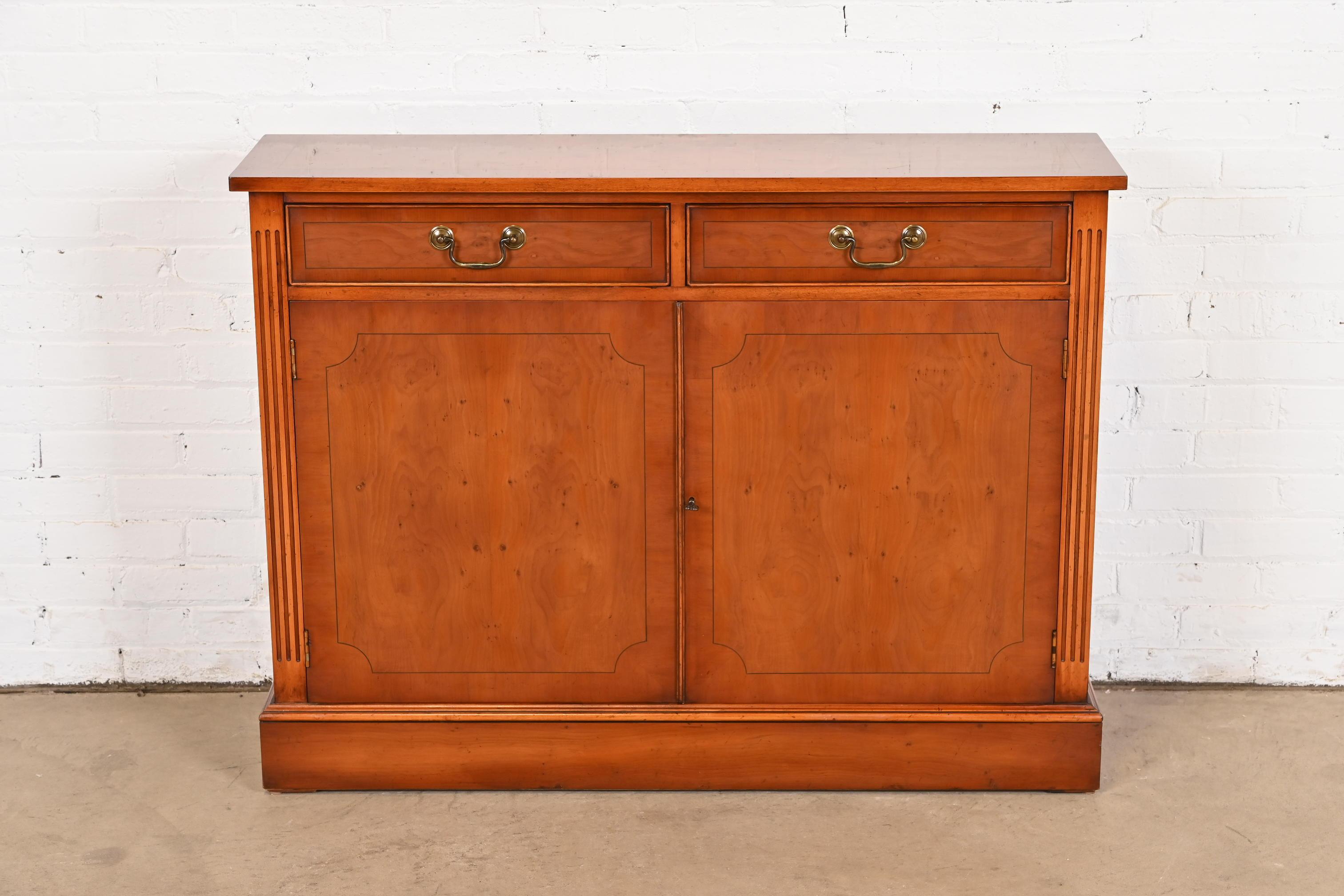 A gorgeous English Georgian style console, buffet server, or bar cabinet

In the manner of Baker Furniture

USA, Circa 1980s

Banded book-matched yew wood, with original brass hardware. Cabinet locks, and key is included.

Measures: 45