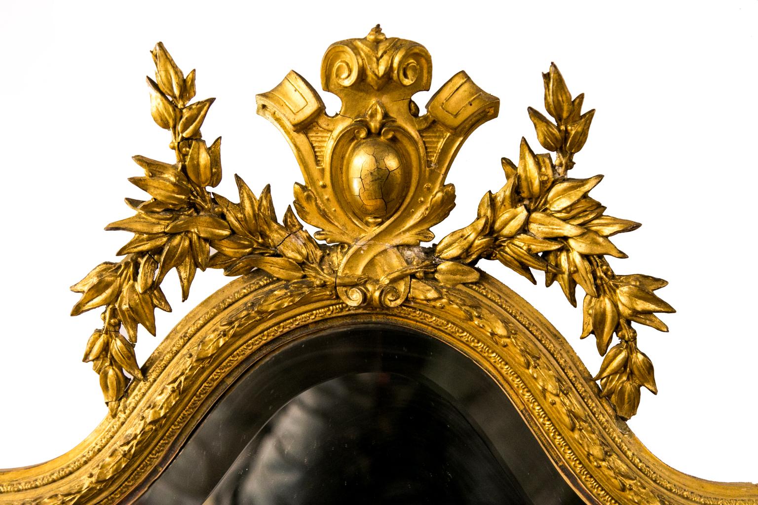 Le miroir Girandole anglais doré est biseauté et entouré de moulures de feuilles appliquées. Il est doté d'un grand écusson floral et d'une base.