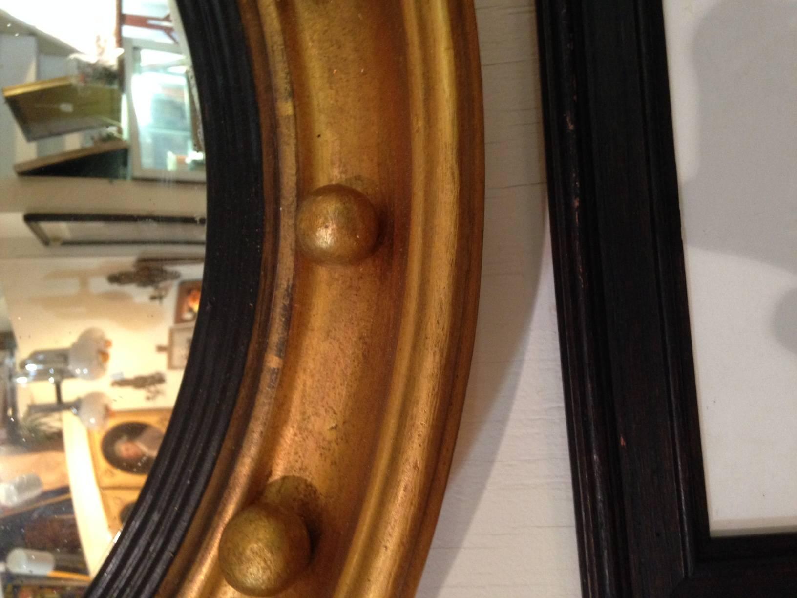 English Regency gilt bullseye mirror, circa 1820-1830, the deep frame with a series of spherules encircling an ebonized and reeded liner and a convex mirror glass. Glass appears to be original; gilt has been refreshed. Minor shrinkage cracks