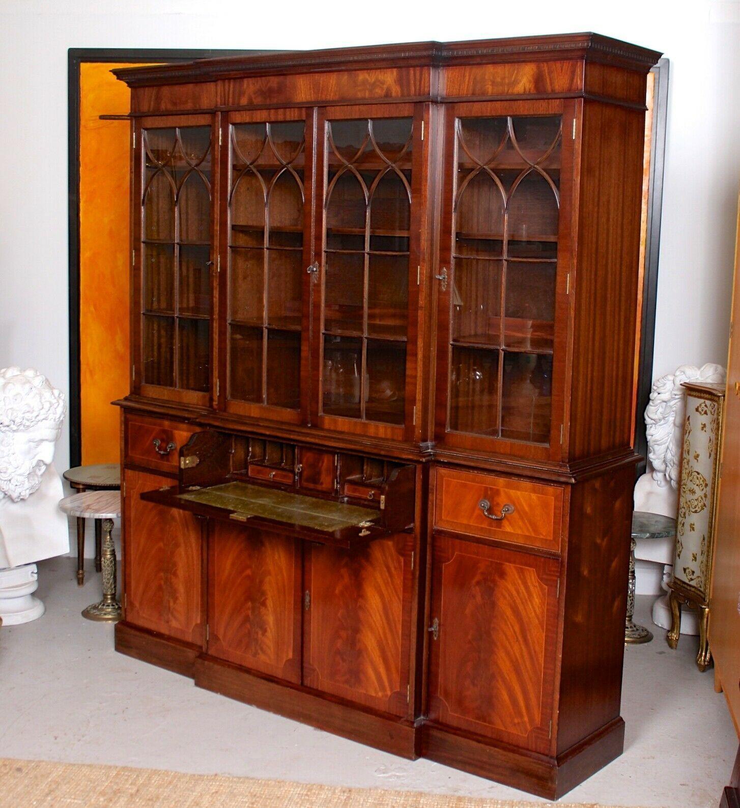 A large fine quality mahogany glazed breakfront secretaire bookcase.
The upper section with a dentil cornice above four astragal glazed doors enclosed shelving and interior lighting. The lower section with chamfered edges and fitted a central