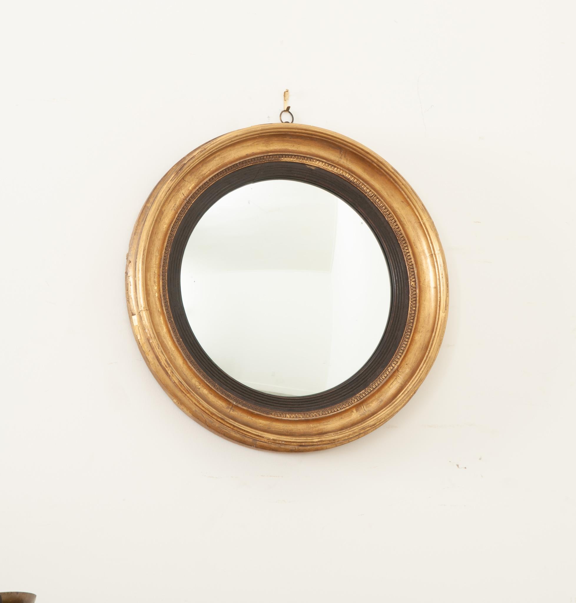 A handsome convex mirror crafted in England during the 1820’s at the end of the Georgian era. The round molded gold gilt frame has a lovely patina and secures the antique mirror plate firmly. The mirror has a slight convex and a clear reflection