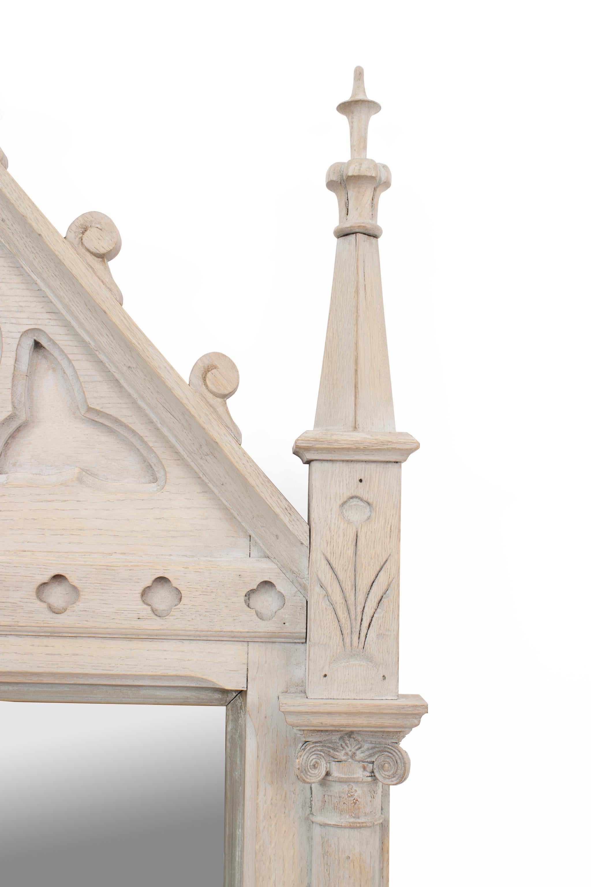 English Gothic Revival (late 19th century) bleached oak wall mirror with column sides ending in finials centring an arch frame with cut-out design.
 