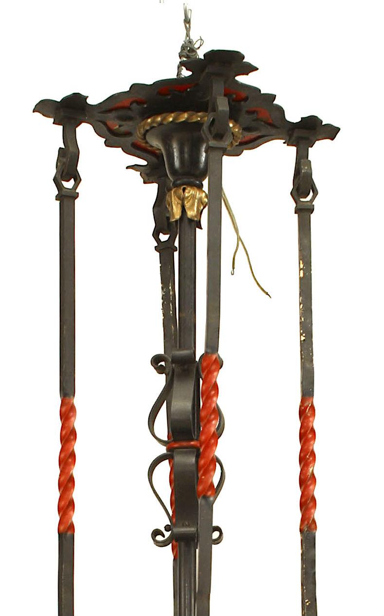 Englischer 8-flammiger achteckiger Kronleuchter aus Schmiedeeisen im gotischen Revival-Stil (1920er Jahre) mit Glimmerschirmen und dekorativ bemalten Schilden und Schnecken mit 5 Ausläufern eines Baldachins.
