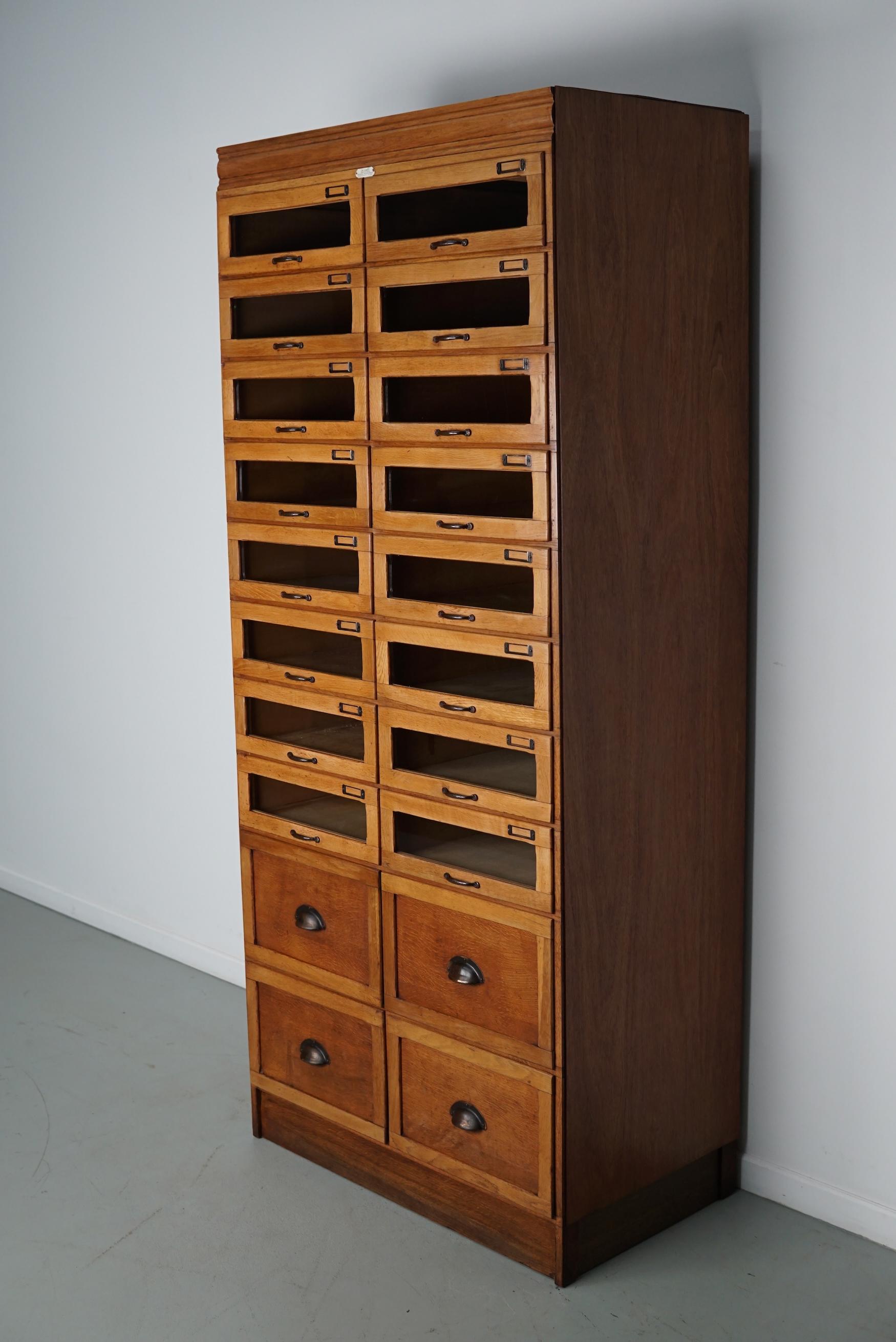 Questo mobile da merceria vintage in rovere risale agli anni '30 ed è stato realizzato in Inghilterra. Presenta una struttura in legno con cassetti in vetro e quattro grandi cassetti chiusi sul fondo. Le dimensioni interne dei cassetti sono: DWH 41