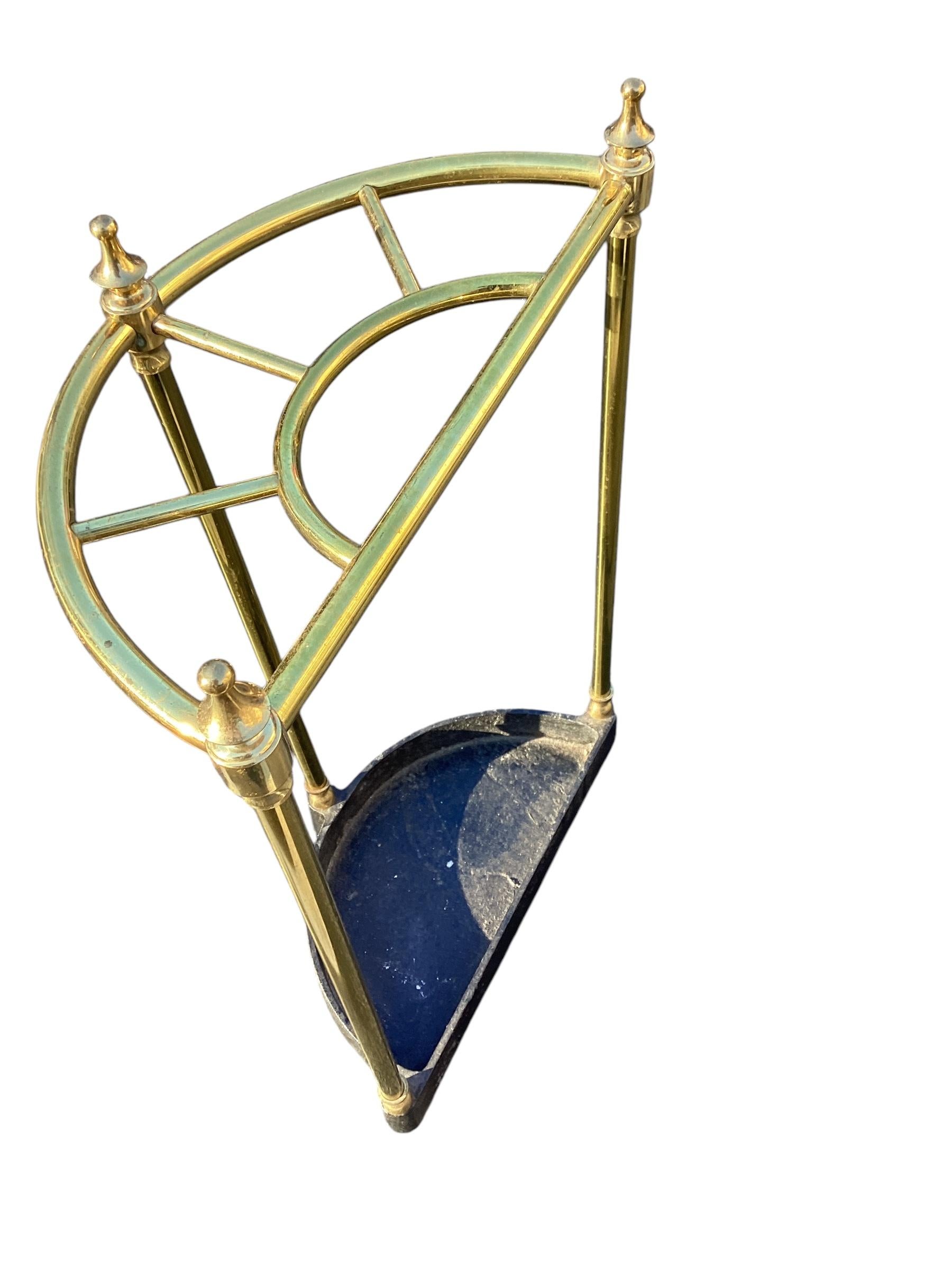 Porte-parapluie ou bâton demi-rond en laiton et fonte. Construction demi-ronde avec des colonnes en laiton se terminant par un fleuron en laiton moulé.