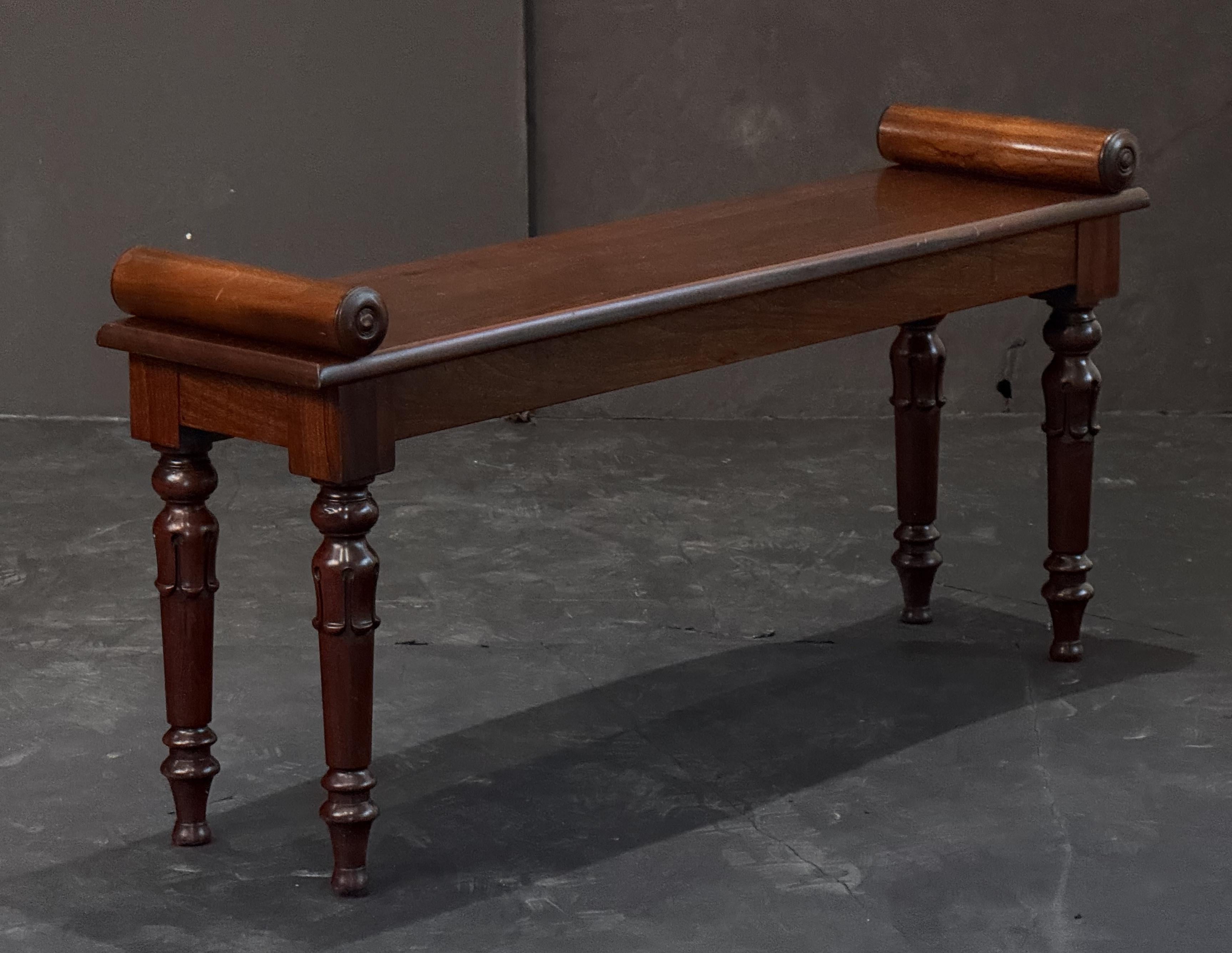 A fine English hall bench or window seat or stool of mahogany from the 19th century, featuring turned handles at opposing ends over a long plank seat and set upon four turned legs.

Dimensions:

H 20.5 inches
W 42.32 inches
D 10.75 inches

SH 18.13
