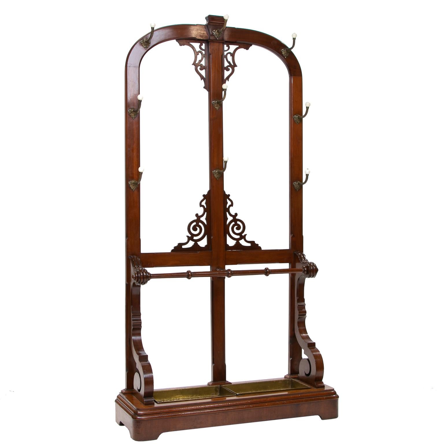 English hall stand, circa 1850
English mahogany hall stand from the 1850s. Solid mahogany frame with an arched top and elaborate pierced fretwork. There are nine decorative brass hooks and umbrella stand with brass drip trays. Turned stick stays