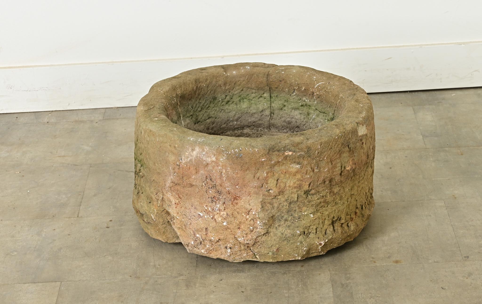 Un antico e sostanzioso abbeveratoio inglese in pietra arenaria, caratterizzato da una meravigliosa texture dovuta all'intaglio a mano e alla patina sviluppata da una vita all'aperto. La forma circolare, anche se irregolare, è bassa e larga per