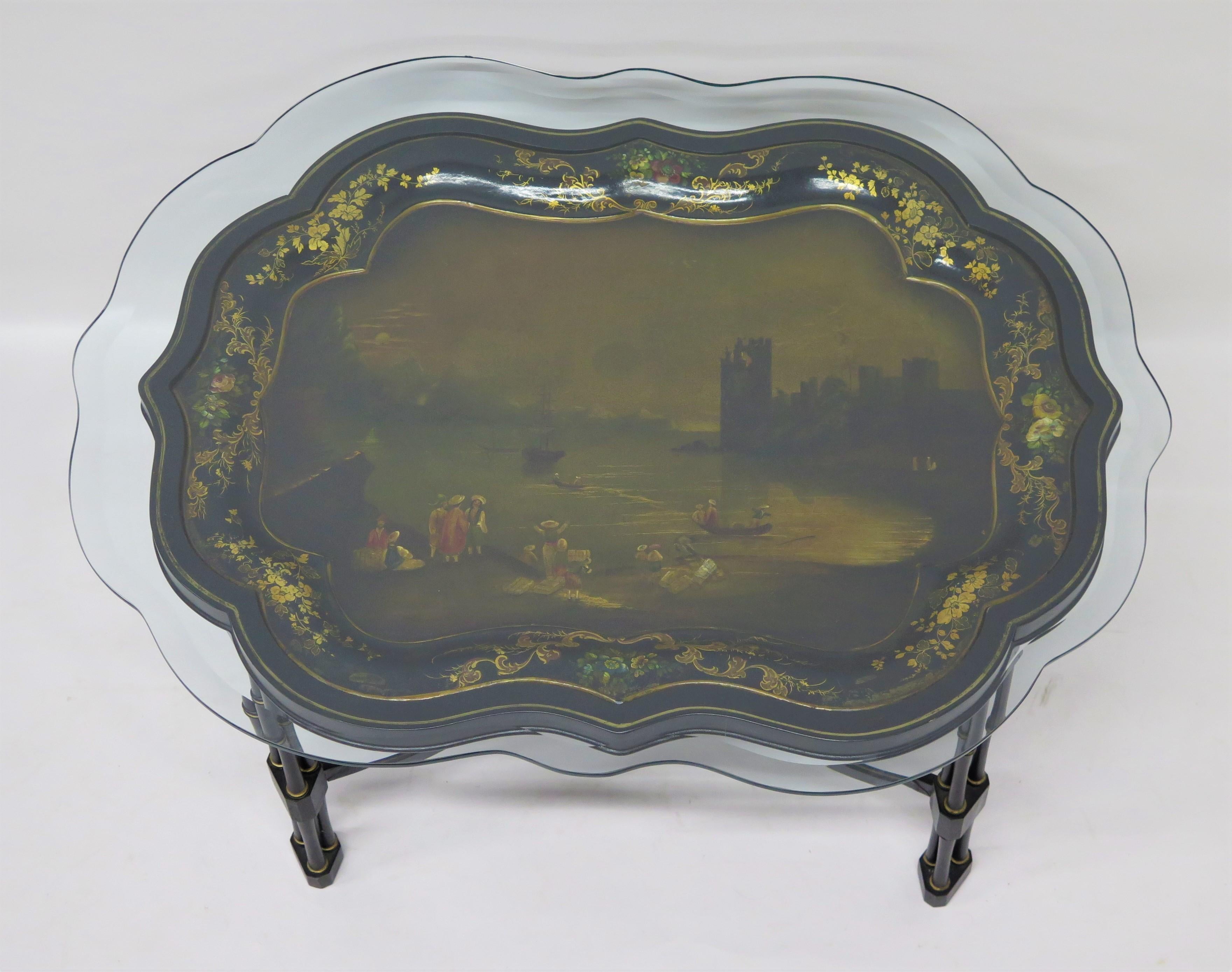 an English hand-painted papier-mâché tray on custom faux bamboo black lacquer and gilt stand depicting a beautiful landscape / lake scene with people, several boats, and a romantic castle ruin along the far shore, shaped border with gilt trim