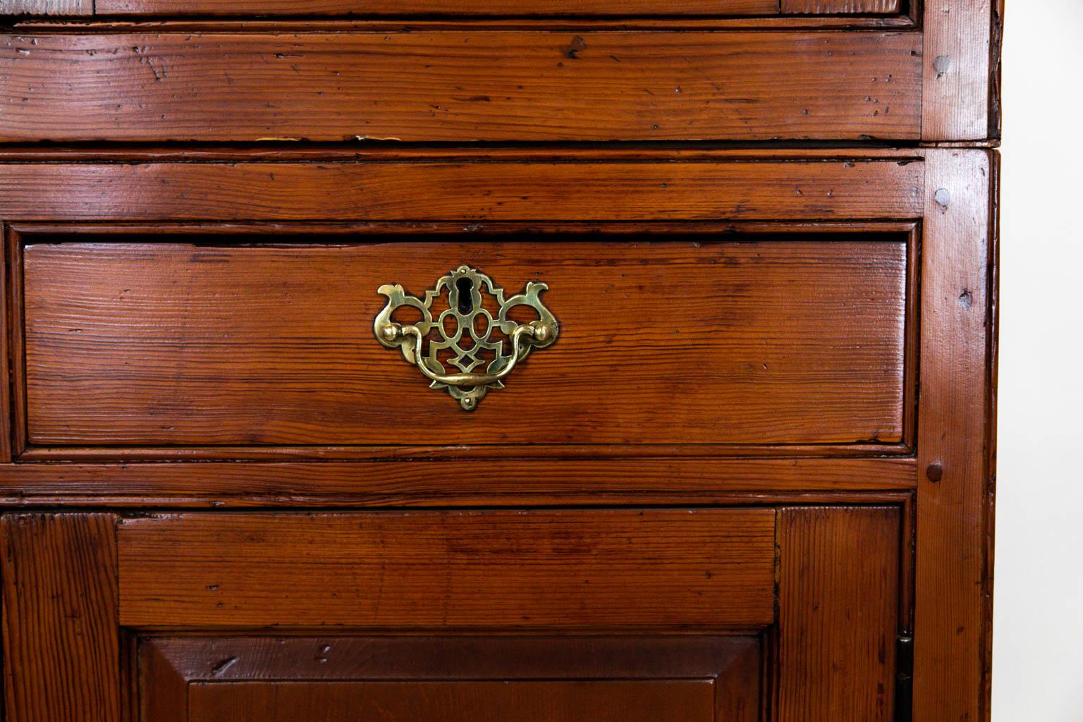 The cornice, feet, and hardware on this beautiful cupboard are later. The upper and lower doors have raised panels. The four doors and drawers are framed with simulated incised beading.