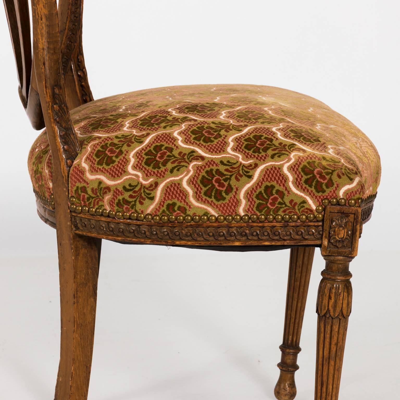 English walnut Hepplewhite style chair with shield back and reeded legs. Small rosette carved banding running along the edges of the top railing. Carved splats with acanthus leaf decor. The condition of the chair is fair, a lot of nicks, and patches