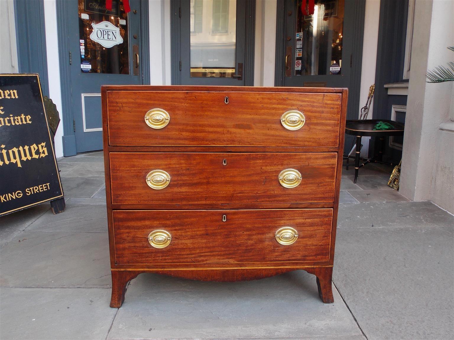 English Hepplewhite mahogany diminutive chest with three drawers, original oval brasses, cross banding, satinwood string inlay, and terminating on carved scalloped skirt with the original splayed feet. Secondary wood consist of oak. Late 18th