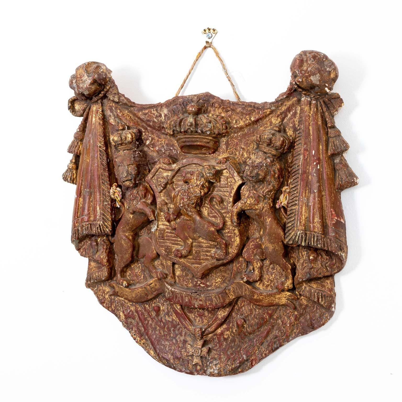 This captivating early 20th Century plaster English heraldic plaque boasts a regal ensemble of crowned lions, a prominent cross, and elegantly draped swags adorned with delicate tassels. Crafted with meticulous detail, it exudes an air of grandeur