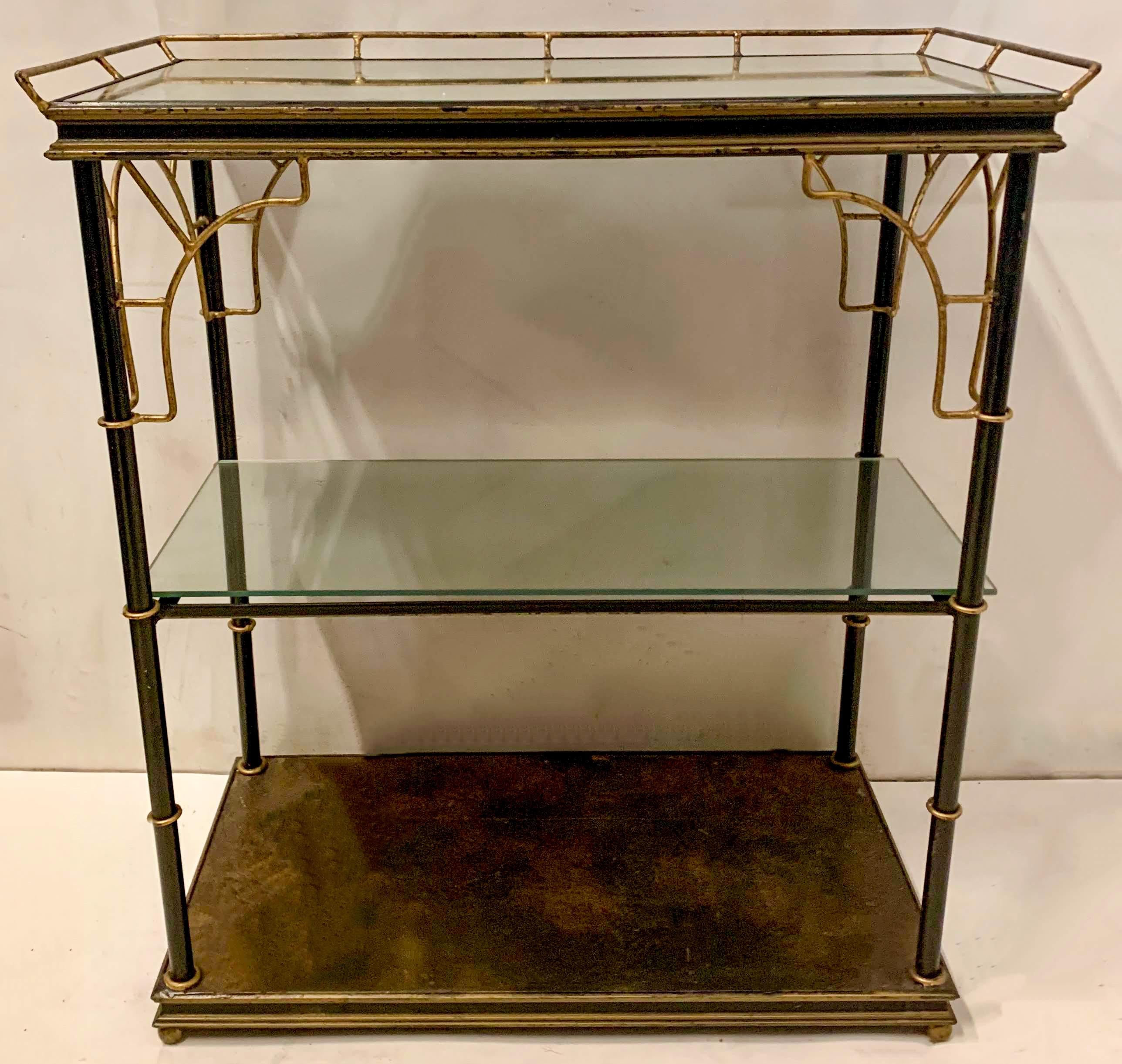 This is an English Hollywood Regency Era tole faux bamboo mirrored etagere. The supports are ebonized metal, while the corner faux bamboo supports are brass. Each shelf is a removable mirror. It shows some age wear to the frame that is more in line