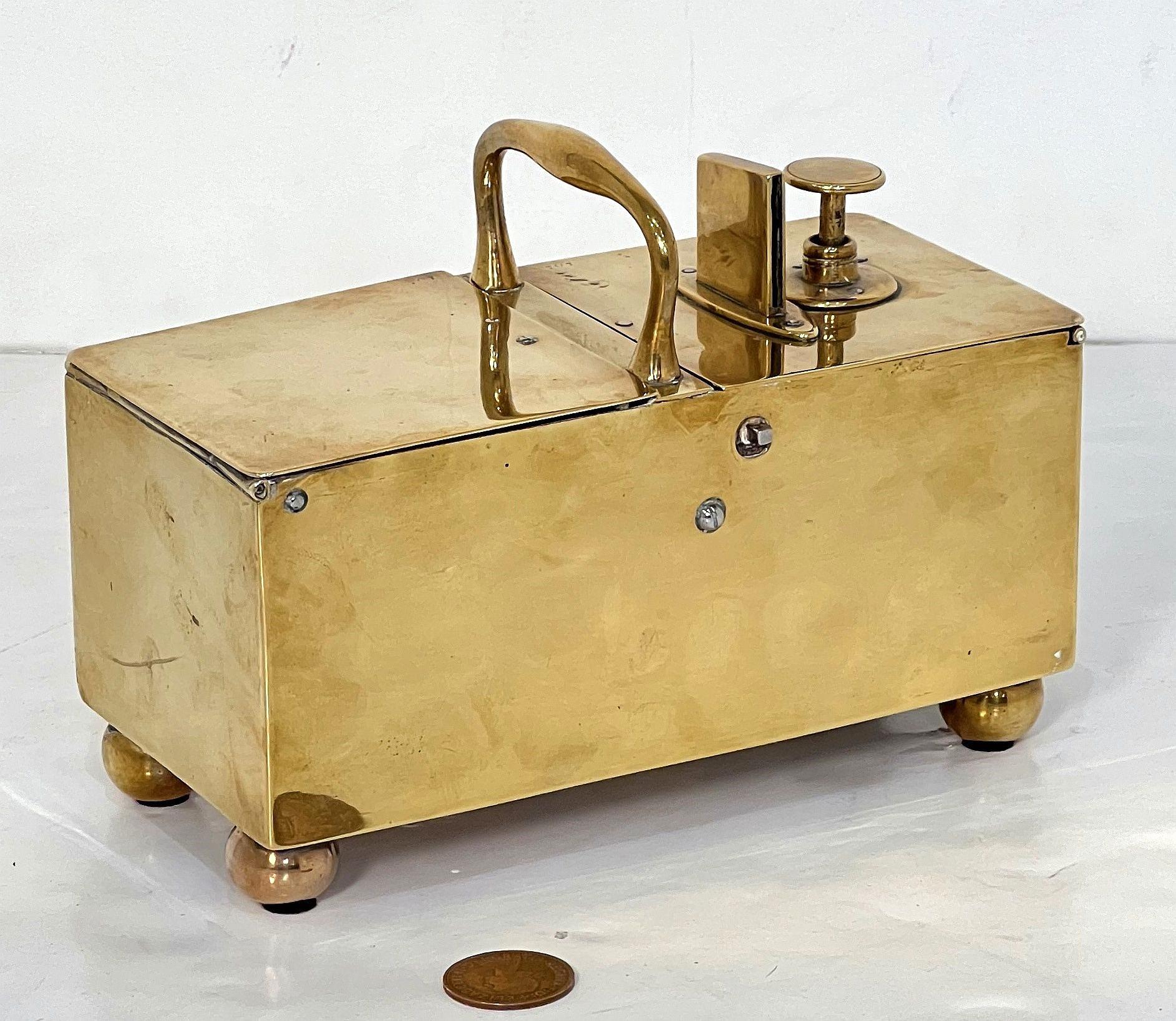A fine English honesty box or tobacco dispenser of brass from the Georgian era, circa 1820 - the rectangular brass box featuring a double-hinged lid and two compartments, one for coins and one for tobacco. Standing on round ball feet and includes a