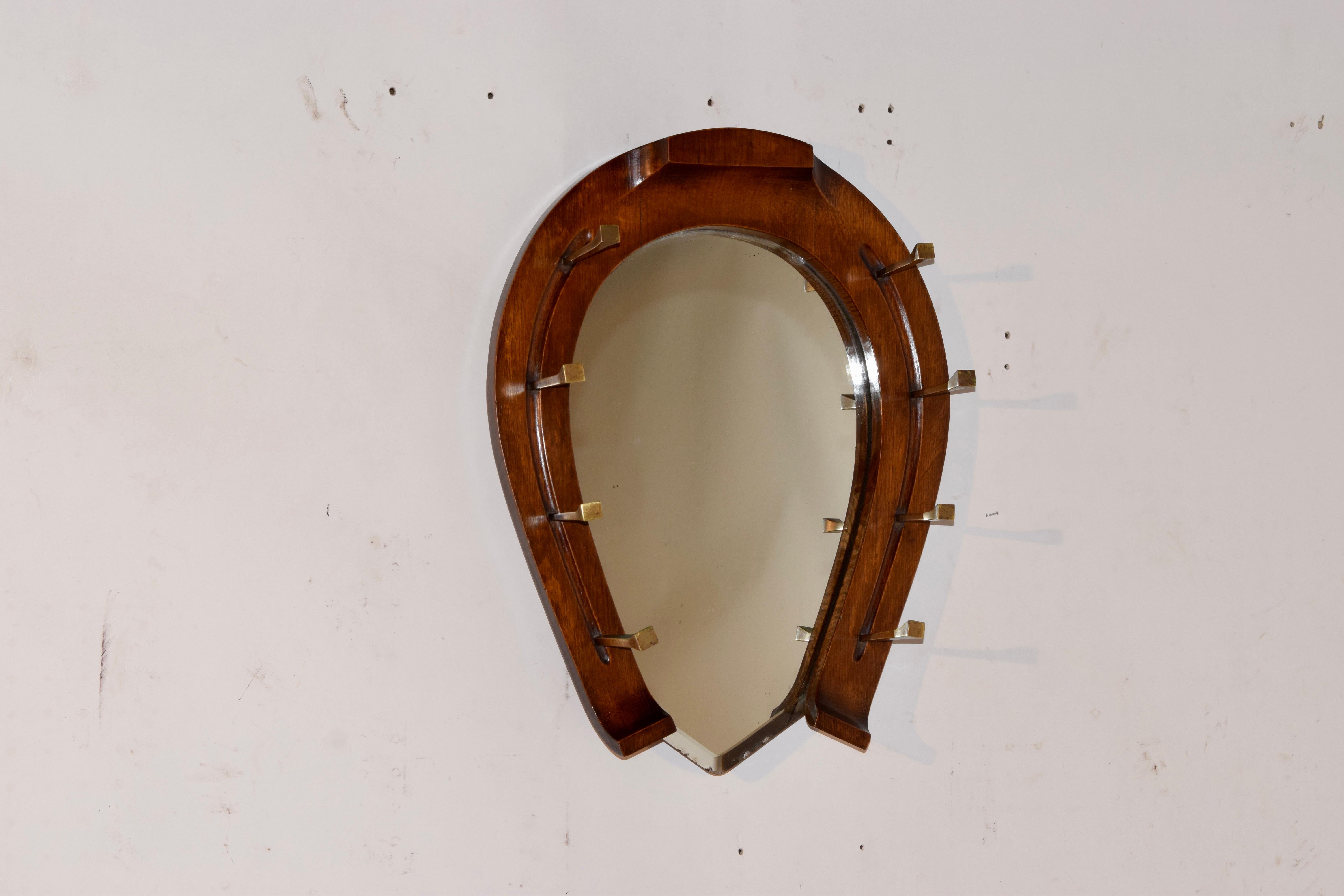English oak mirror in the shape of a horseshoe with hand cast brass hat racks in the shape of horseshoe nails. There is a brass registration mark on the top of the horseshoe dating the manufacture of the piece to May 11, 1878. The mirror is original