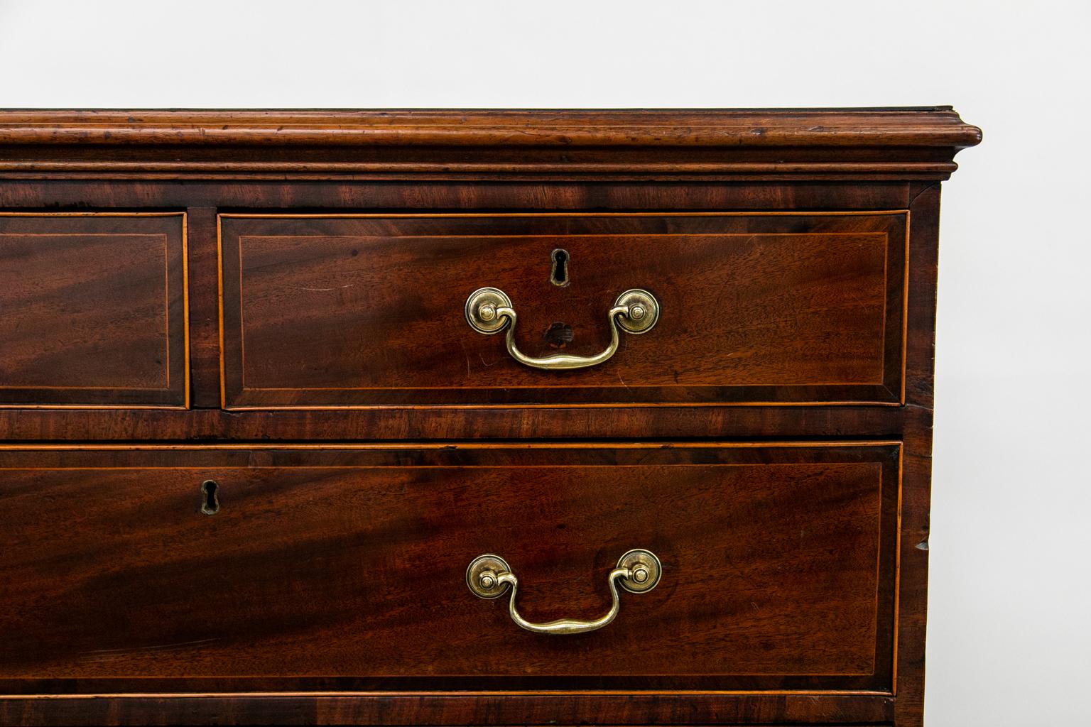 This chest is all original including the brasses. The top and drawer fronts are crossbanded with mahogany and inlaid with French boxwood. The drawers are framed with French boxwood cockbeading. The lock and key are original.