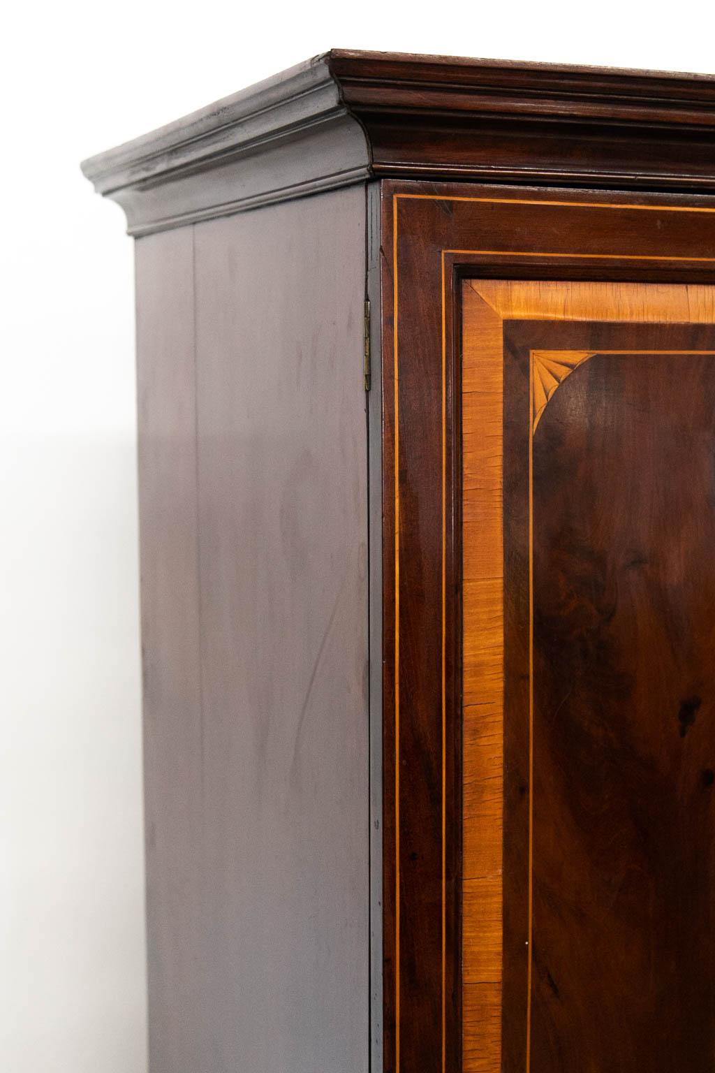 The doors of this linen press have beveled raised panels framed with one inch bee's wing satinwood with boxwood inlay framing quarter fans and a central oval satinwood and boxwood fan. The doors are also inlaid with double boxwood lines. The drawers