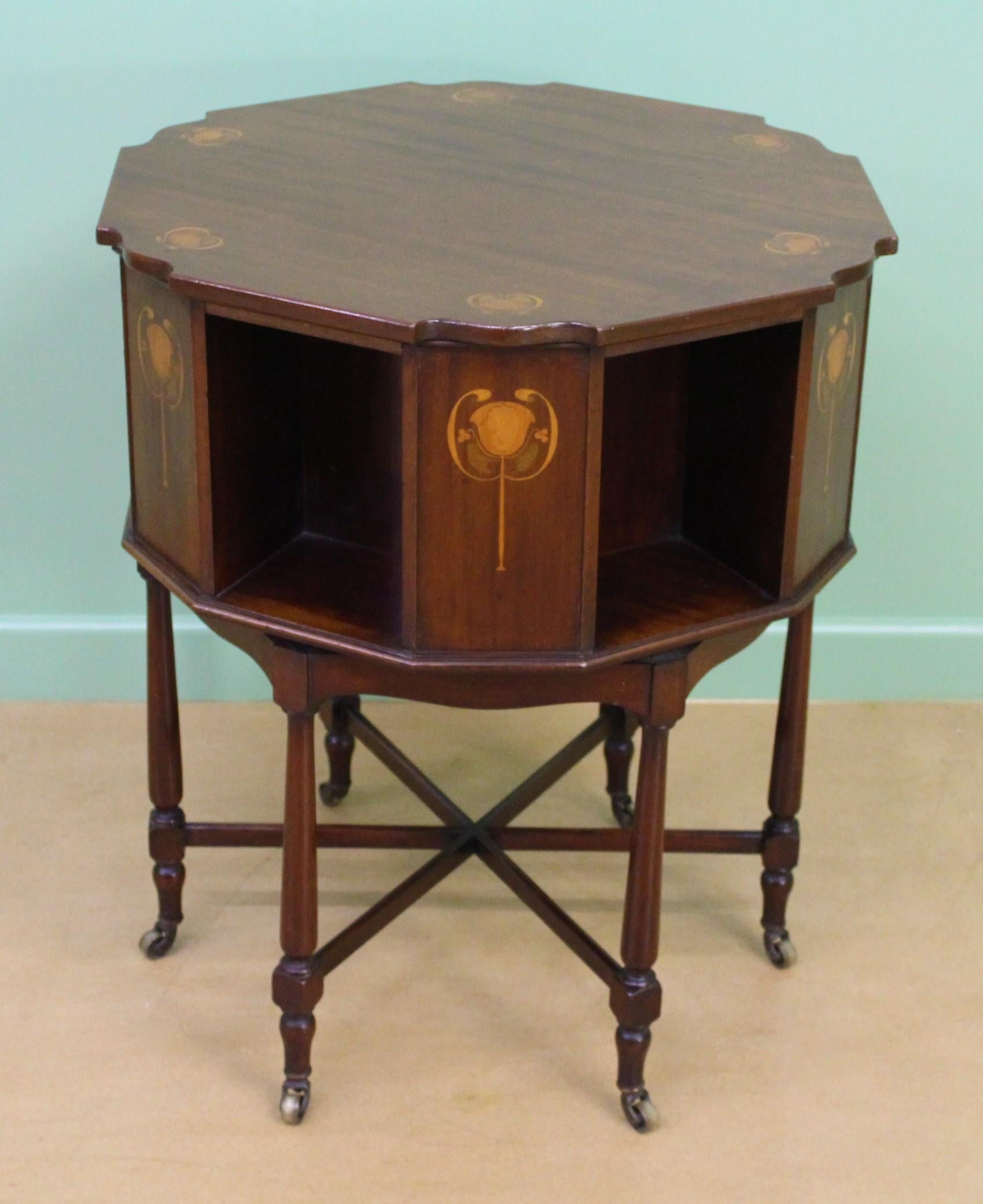 A charming Art Nouveau period inlaid mahogany book table. Well made in solid mahogany and decorated with stylized floral motifs to the top and sides. Standing on 6 turned legs which terminate in their original castors and are united by