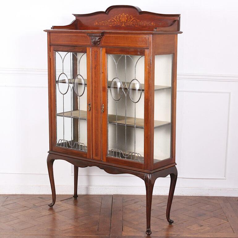 A pretty English inlaid mahogany china cabinet with floral inlay to the top and boxwood and ebony inlaid stringing throughout. An influence of Art Nouveau can be seen in the inlay and leaded glass pattern. The leaded glass doors open to a pair of