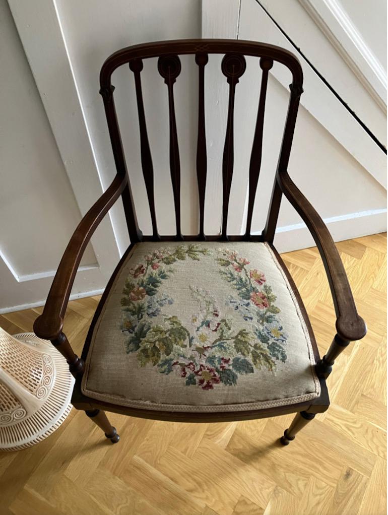 A beautiful English Mahogany Victorian chair with armrests and a unique floral tapestry seat. The chair has elegant, slim carved arms and legs and a spindle back which are inlaid with the finest contrasting marquetry details. 

A beautiful English