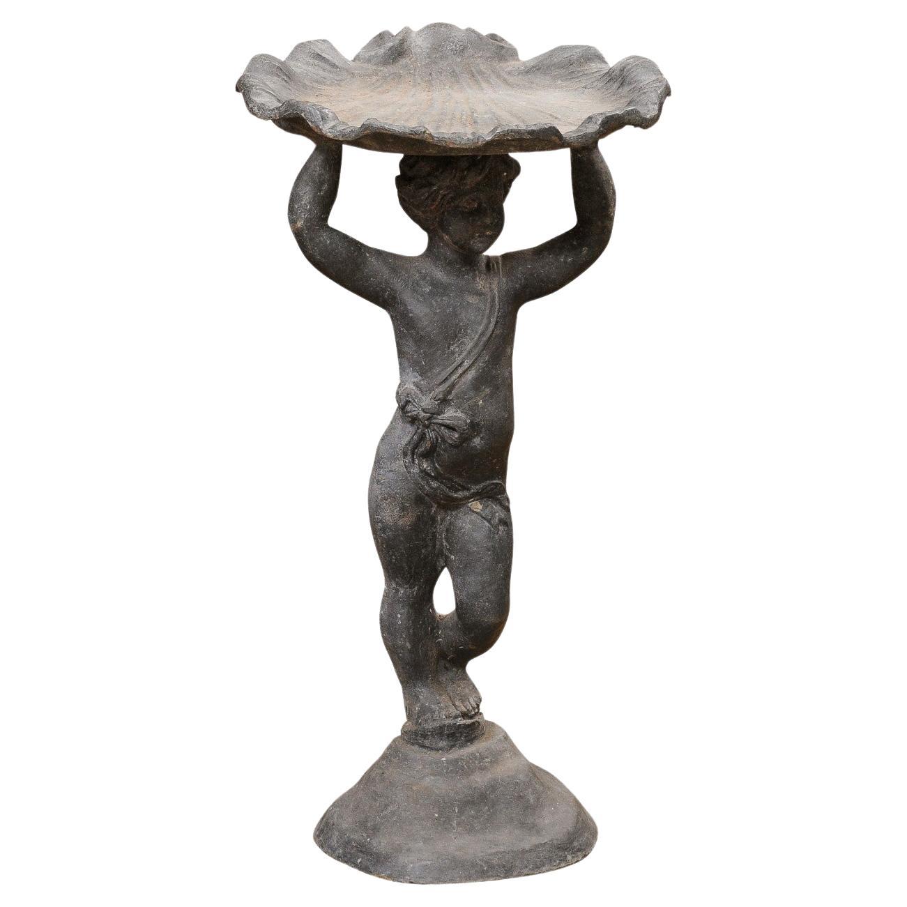 English Iron Greco-Roman Style Standing Cherub Carrying a Sea Shell Bird Bath For Sale