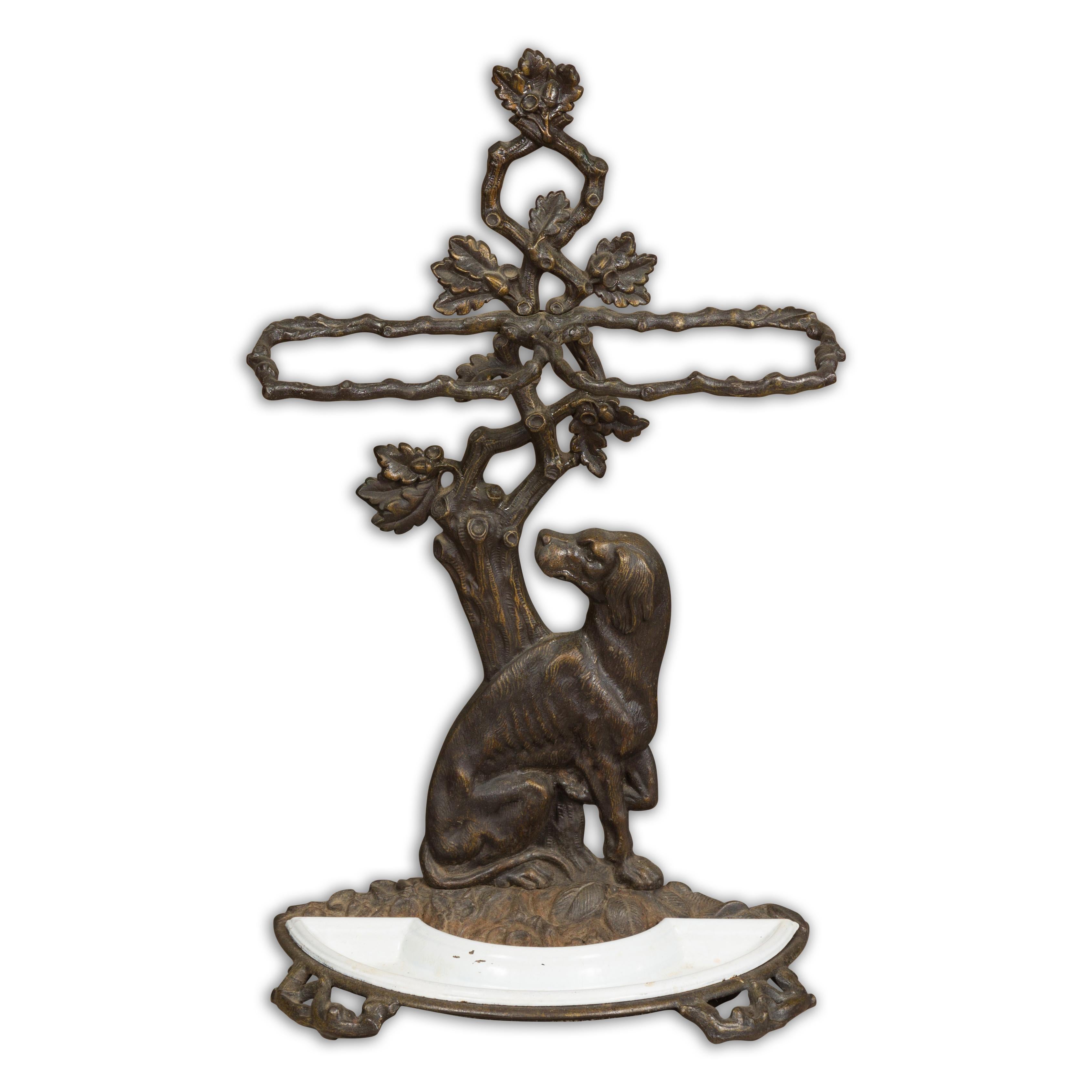 An English iron umbrella stand from the 20th century with dog sitting in front of a tree motif. Add a dash of whimsical elegance to your foyer or hallway with this handsome English iron umbrella stand from the 20th century. Brimming with character
