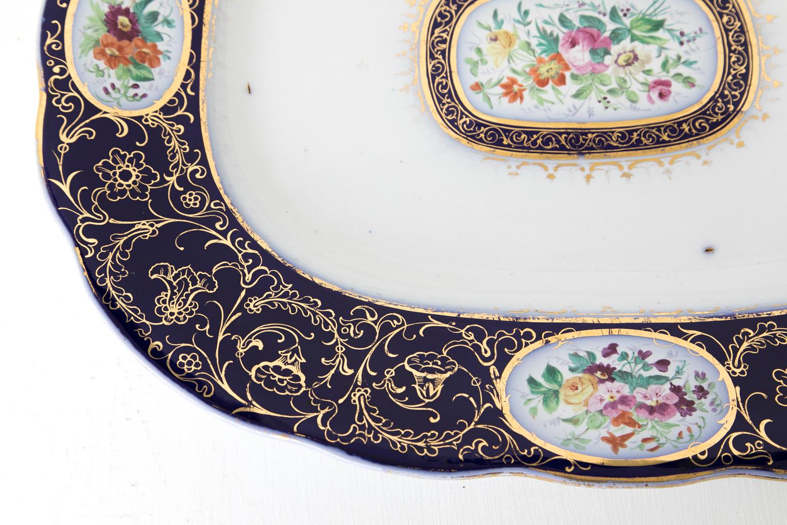 Plat de service en pierre de fer anglais, avec une profonde bordure cobalt avec quatre vignettes florales ovales. Le panneau central présente des motifs floraux entourés de cobalt et de dorure.
   