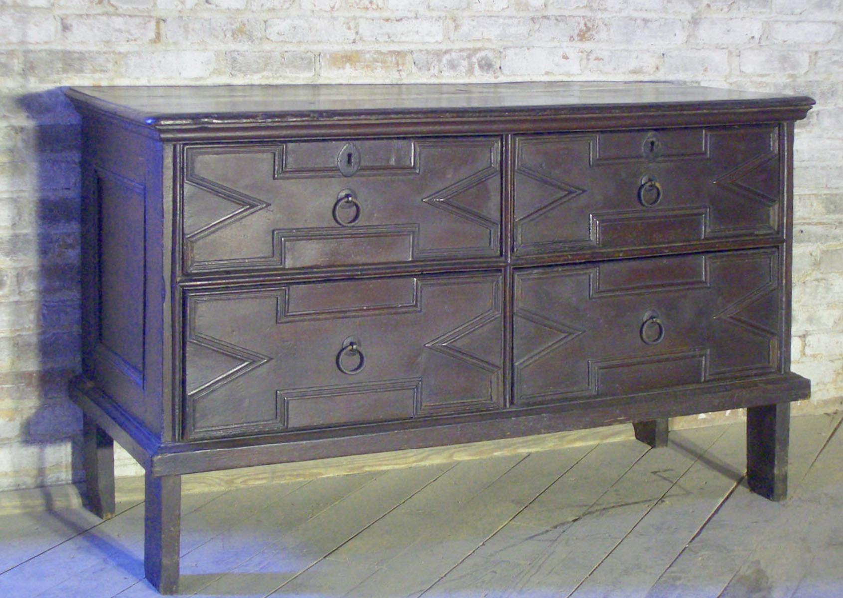 Large and unusual Jacobean commode, the dark stained oak and the elongated body on tall legs give it an elegant streamlined appearance. Four drawers with geometrically molded fronts and simple ring-pulls add to the understated, architectural look.