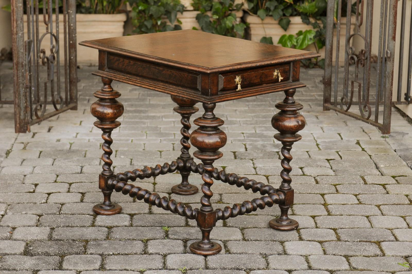 An English Jacobean style oak side table from the early 19th century, with single drawer, barley twist base and side stretchers. Born in England during the reign of King George III, this exquisite side table features a rectangular top with beveled