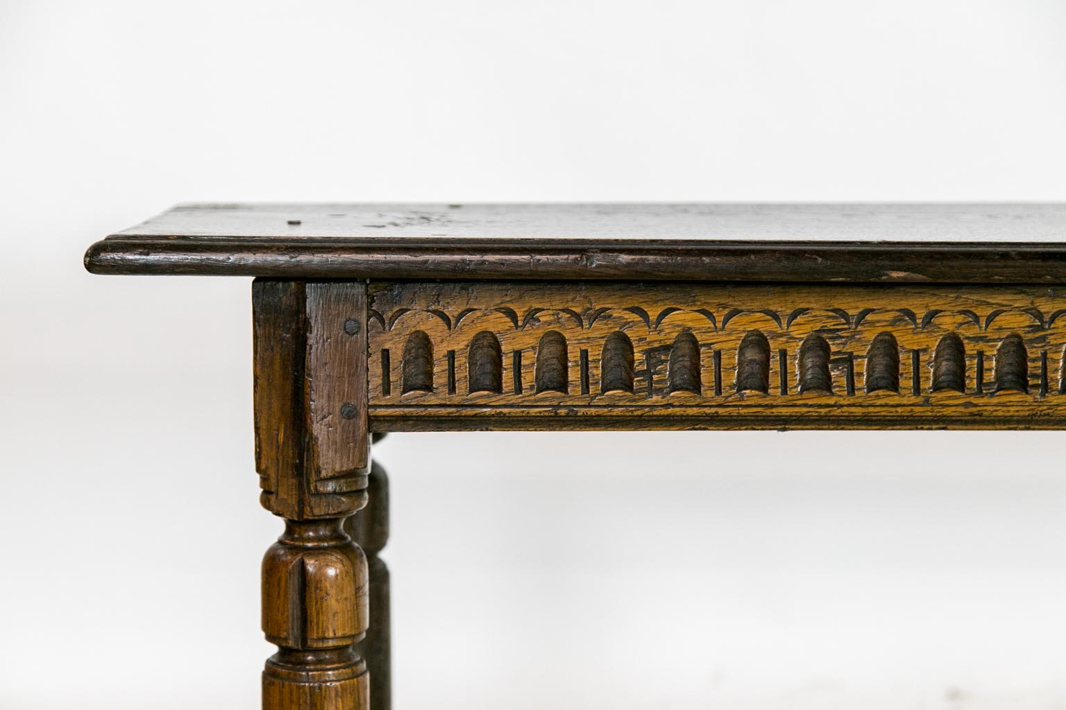 This Jacobean style oak bench has carved repeating stylized arches in the apron and a cross stretcher with exposed peg construction, nice color and patina.
