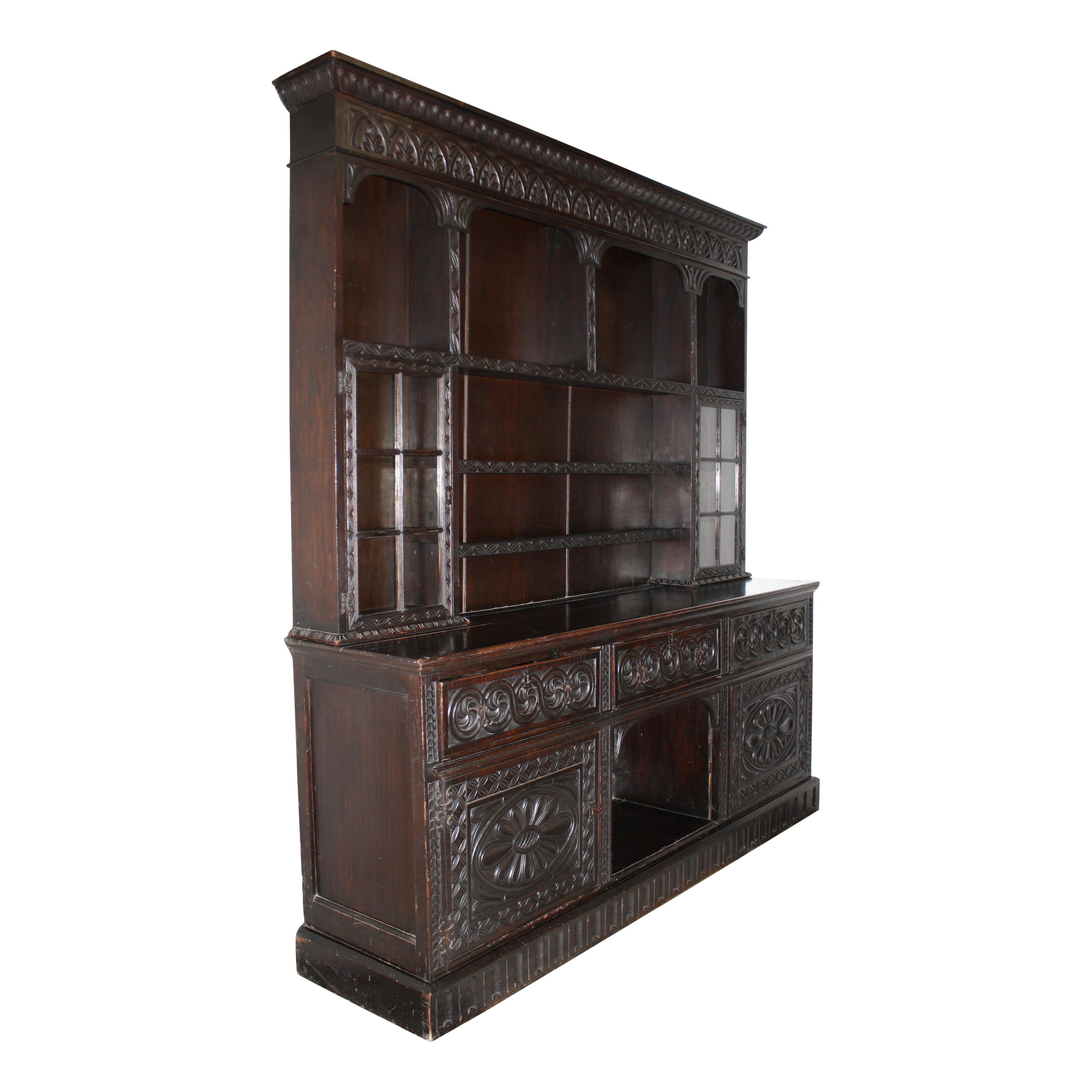 Beautifully carved and of substantial size, this English cabinet is comprised of a lower piece manufactured by James Phillips & Sons of Bristol in the early 20th century and a top hutch, which was masterfully added by Edwards & Roberts of London.