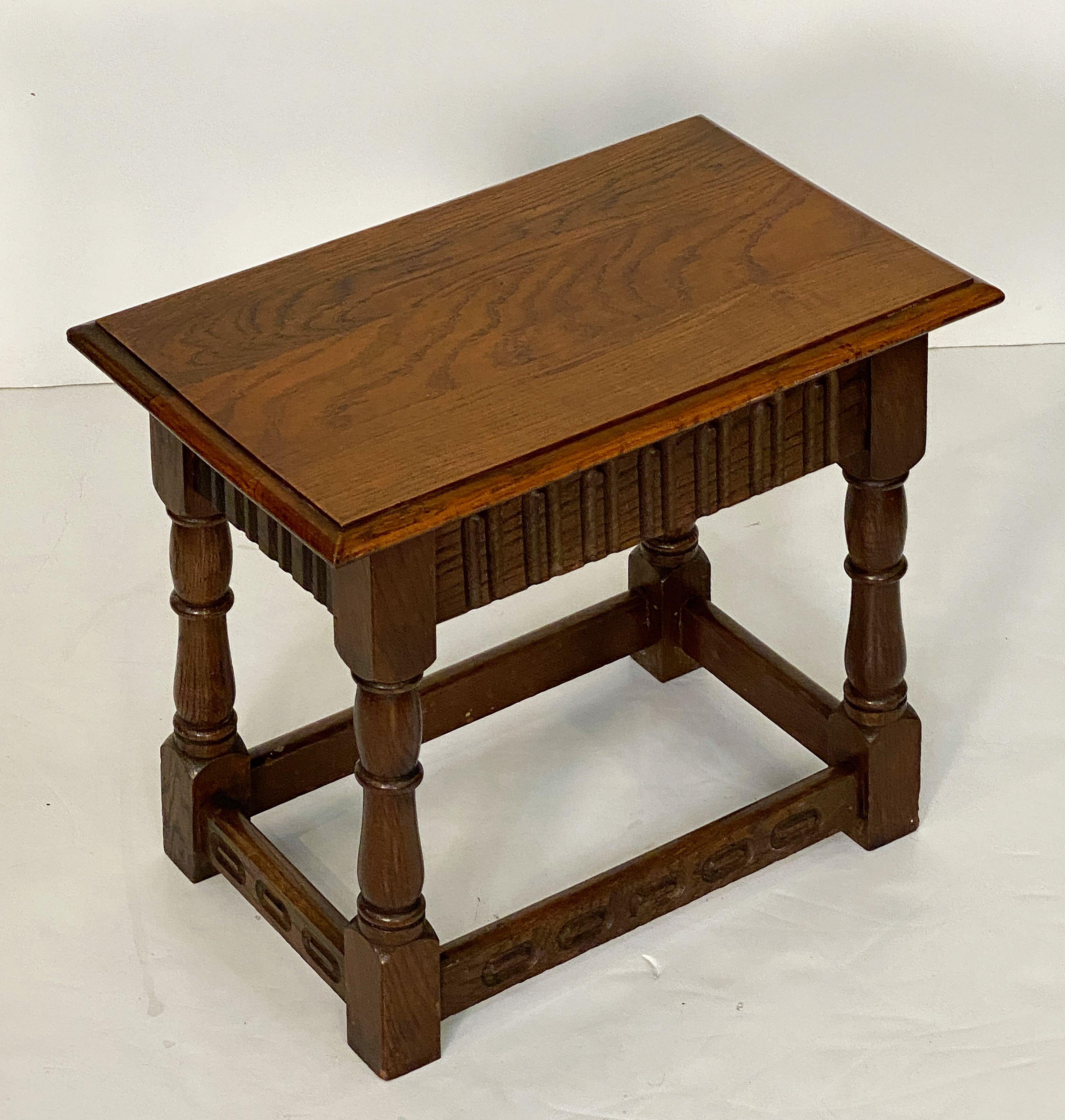 A fine English joint stool or seating bench of well patinated oak, featuring a rectangular top with moulded edge, set upon a stretcher base with a carved design on the frieze and four turned legs.